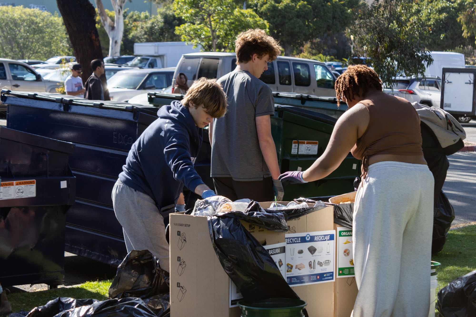 Three people sort trash, recycling and compost during an outdoor event