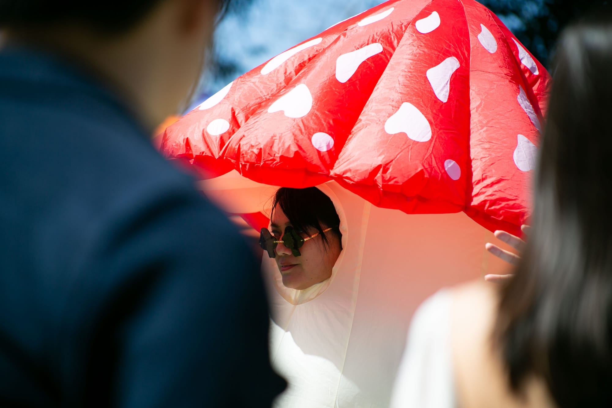 A person wears an inflatable mushroom costume in a crowd.