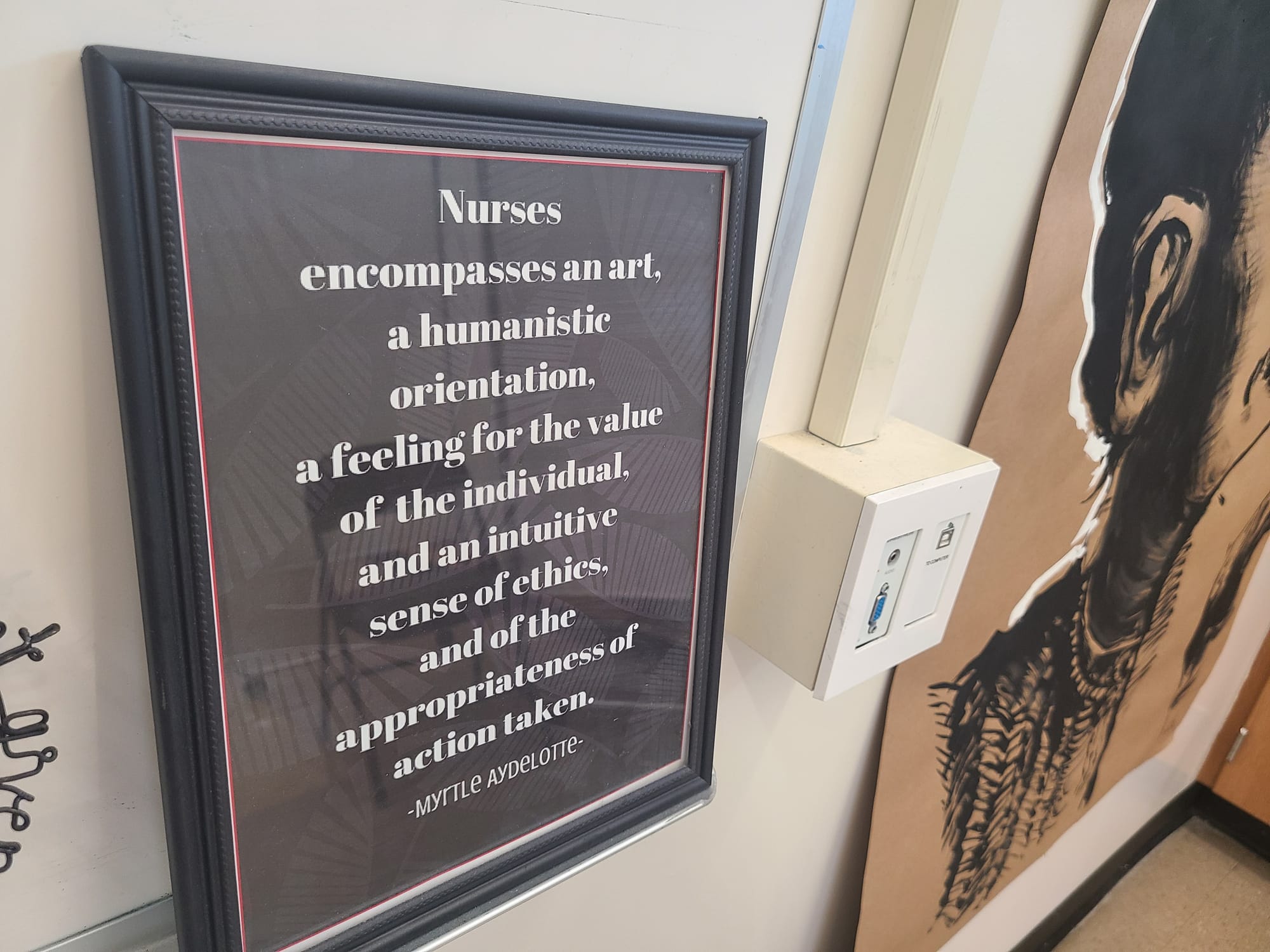 A framed quote says "Nurses encompasses an art, a humanistic orientation, a feeling for the value of the individual, and an intuitive sense of ethics, and of the appropriateness of action taken. -Myrtle Aydelotte"