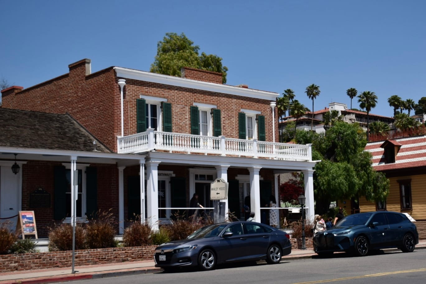 Picture of a Greek revival building with cars parked in front of it. 