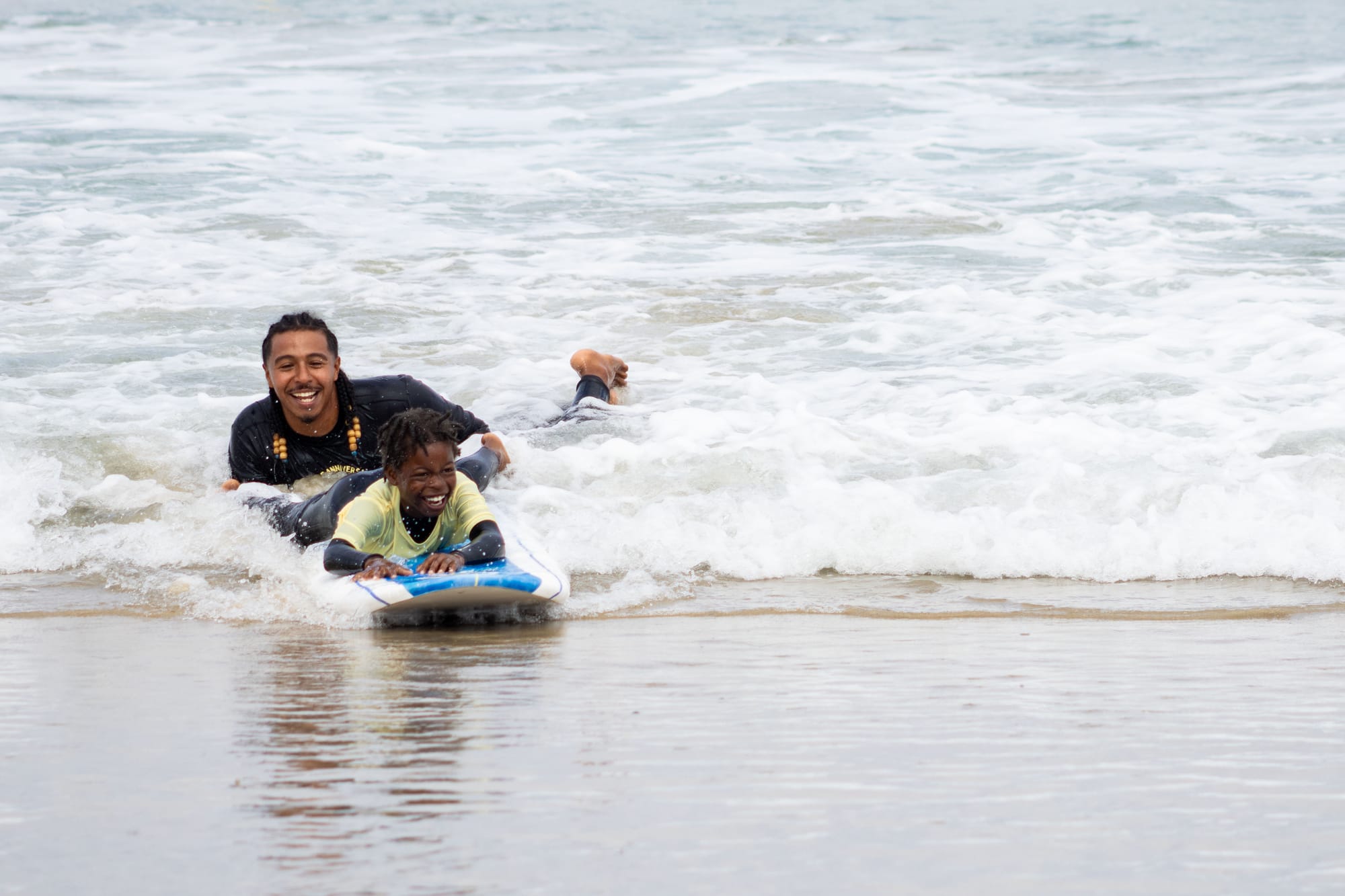 A man and a child catch a wave on a surfboard in the water