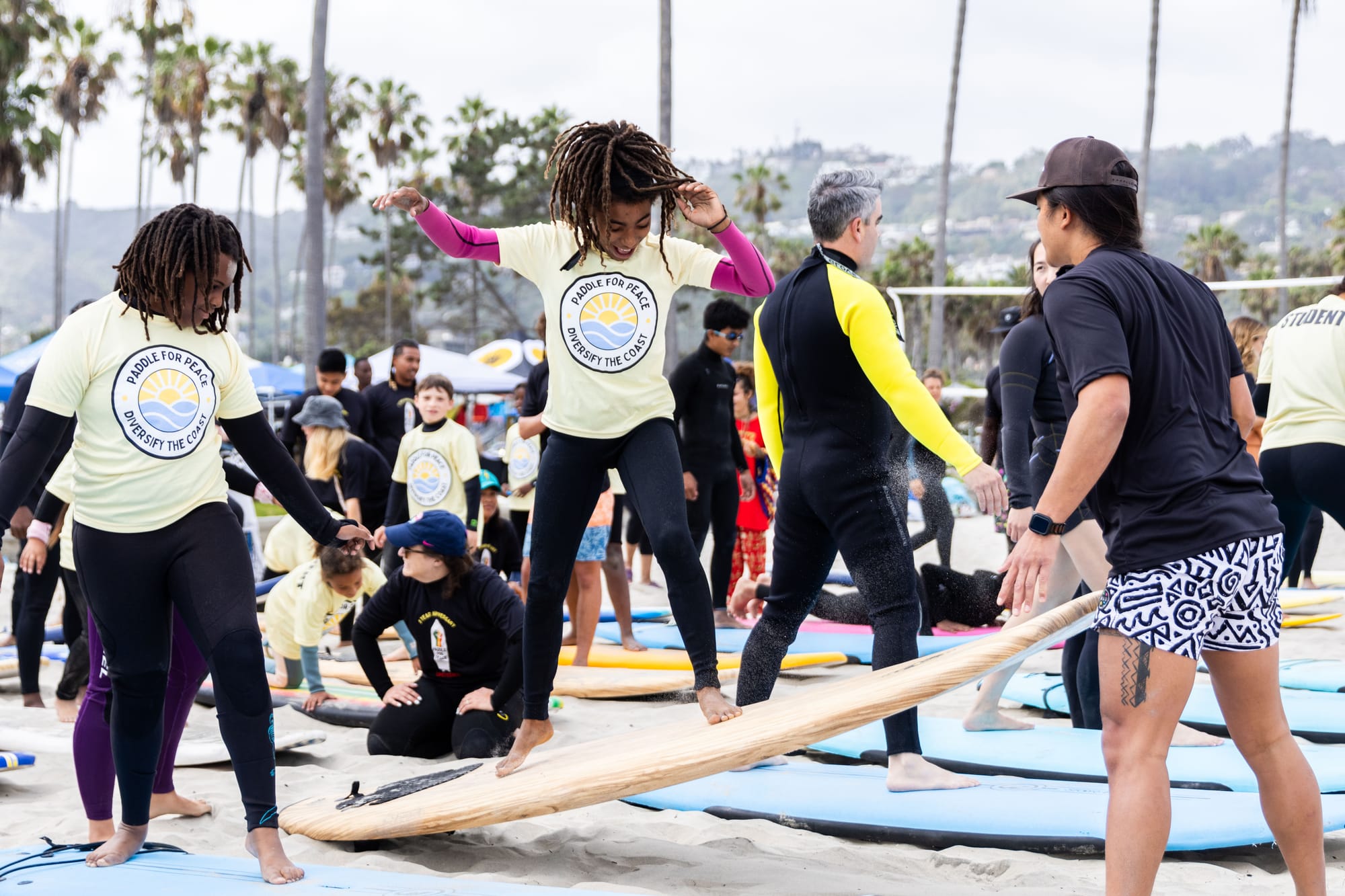 A child practices balancing on a surfboard on the sand