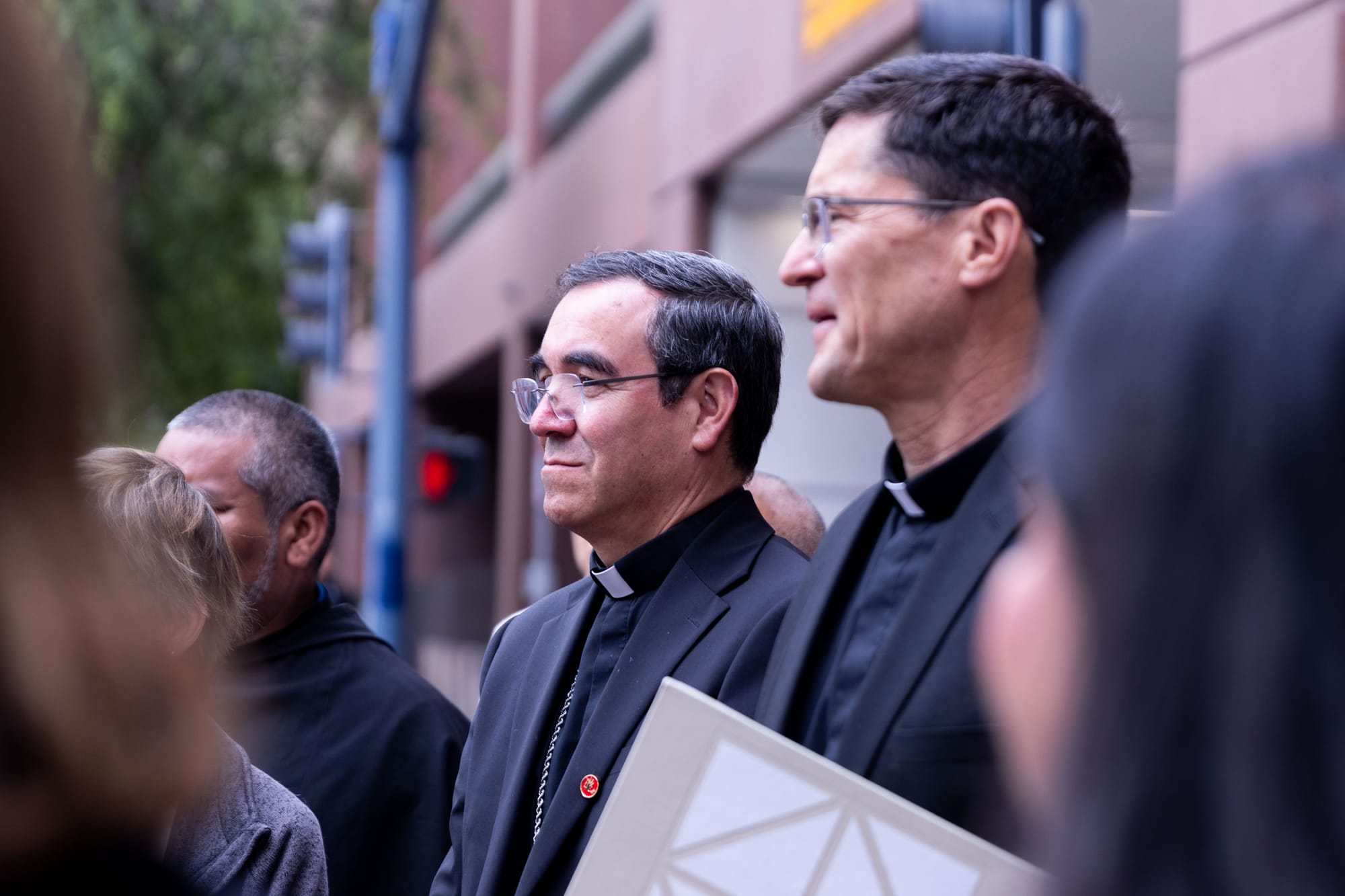 Two men in clergy apparel stand among a group of people