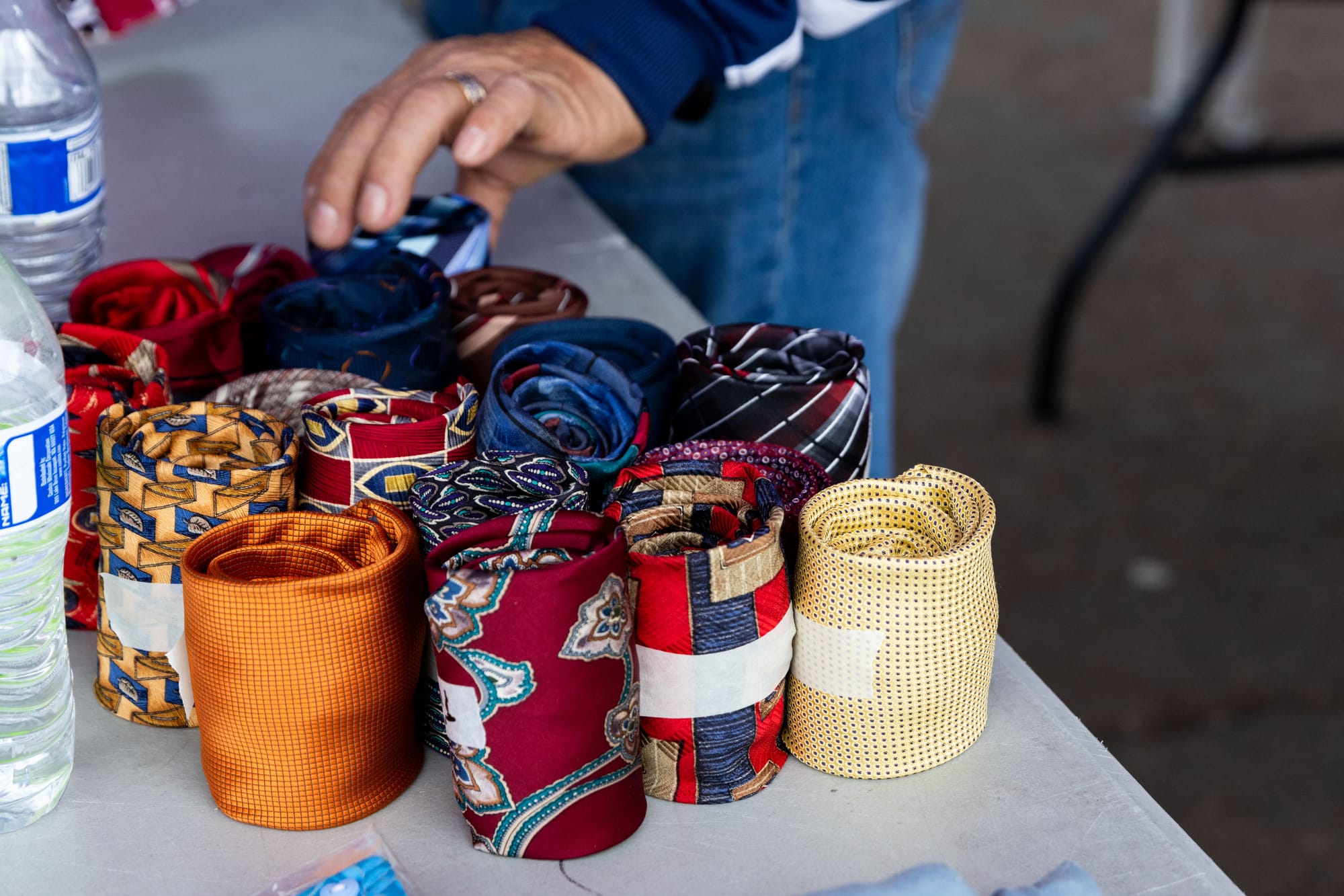 Closeup image of rolled ties and water bottles on a table as a hand sorts them.