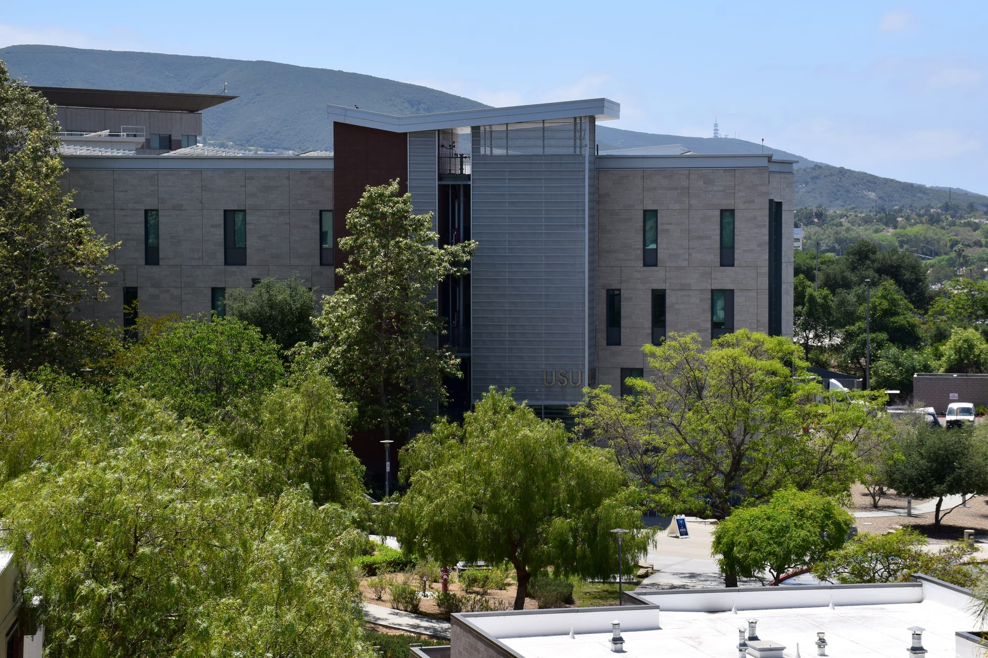 A building outside in front of a mountain and behind trees