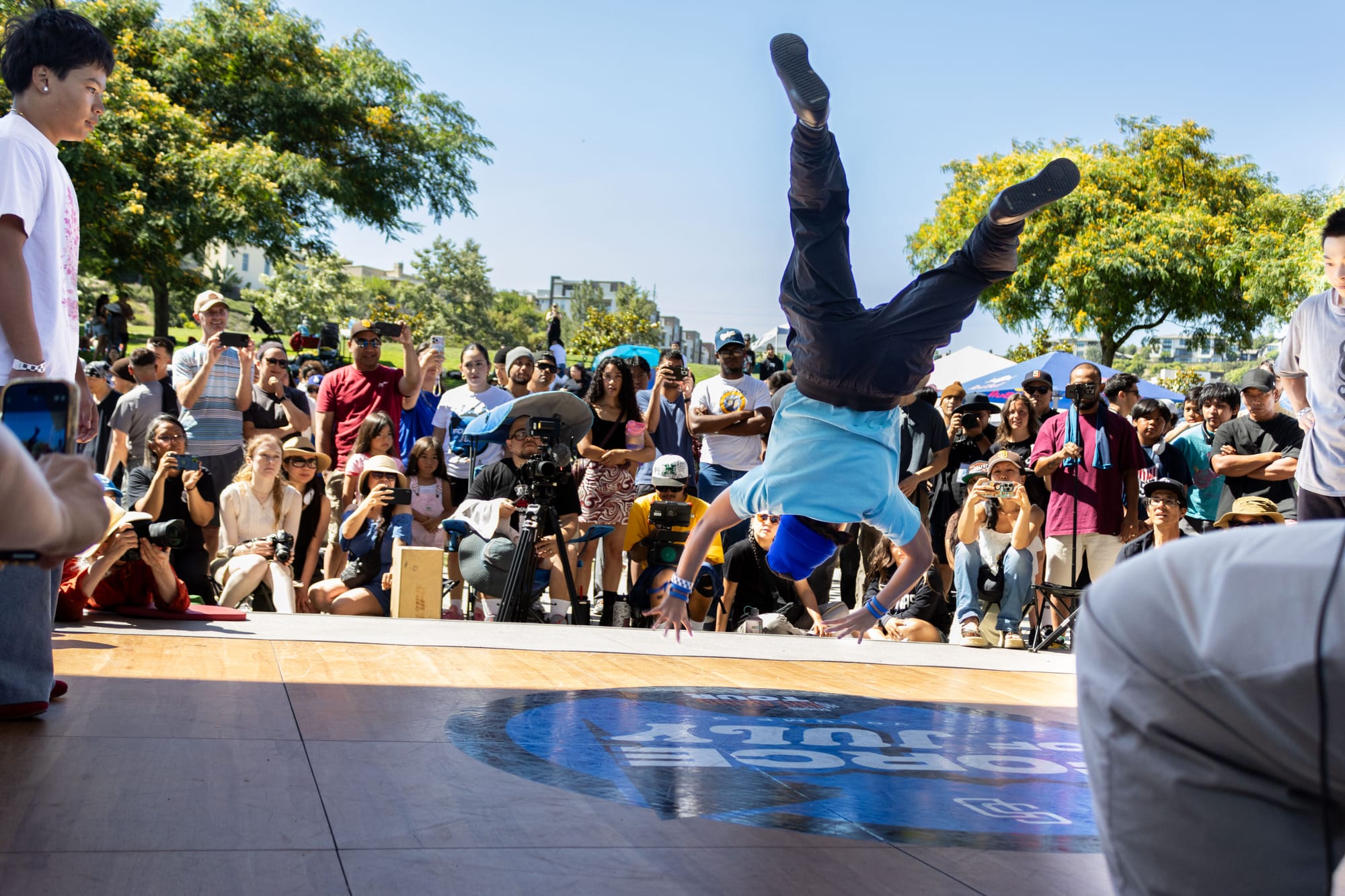 A dancer performs in a breaking competition outside in a park.