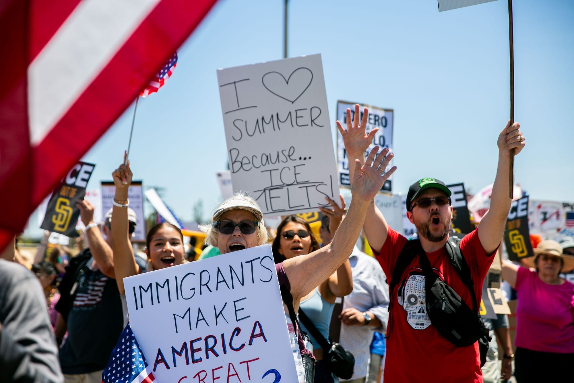 People march holding signs like "I love summer because ice melts" and "immigrants make America great"