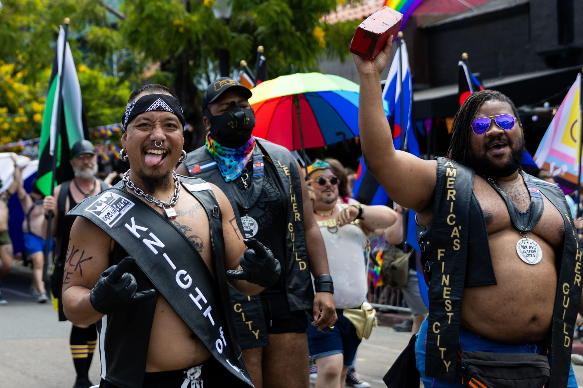 People with leather vests, sashes and stoles walk in a parade