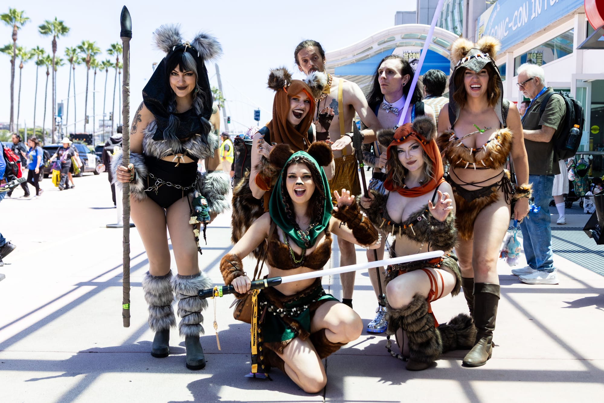 People dress up in Ewok costumes with light sabers and spears outside a convention center
