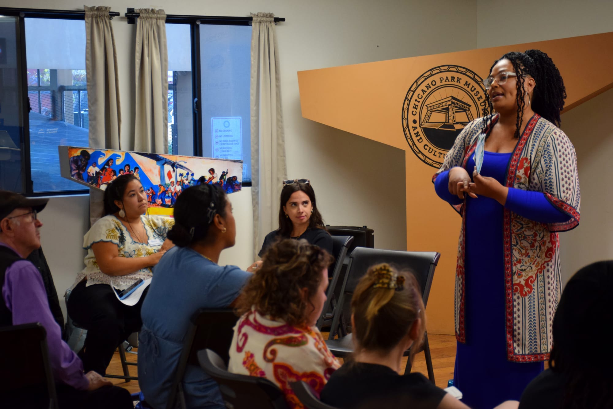 People sit listening to a person during an indoor town hall meeting