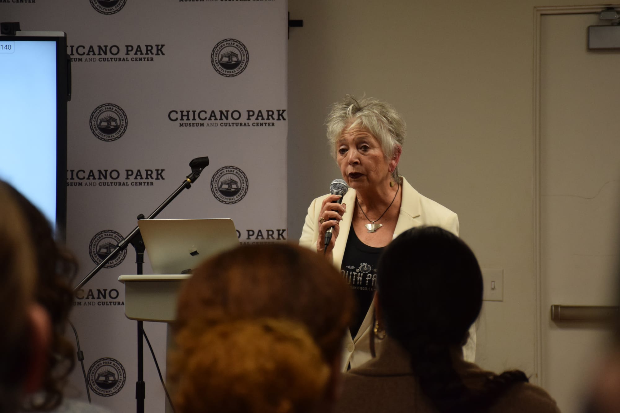 A woman speaks into a microphone at an event