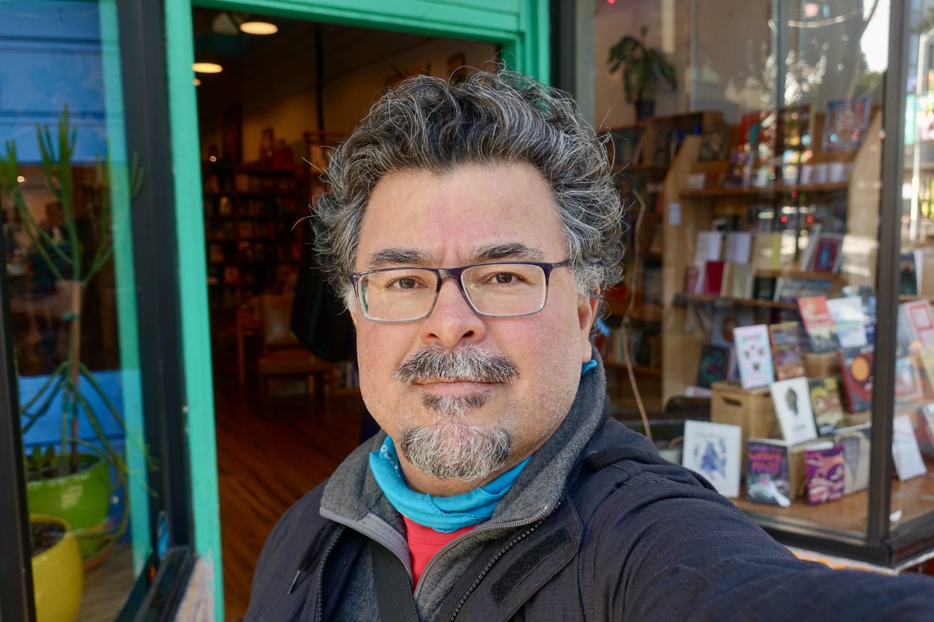 A man poses for a photo in front of a bookshop