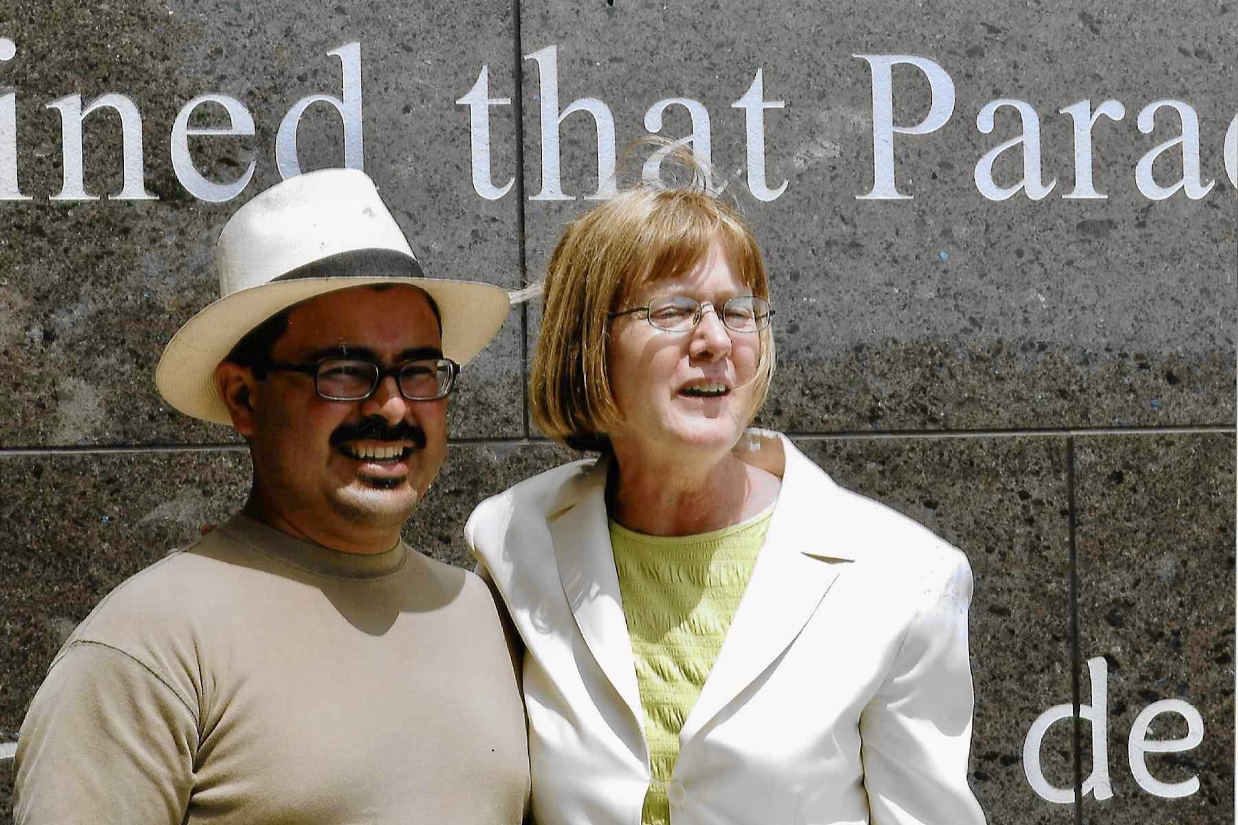 Two people pose for a picture outside a building