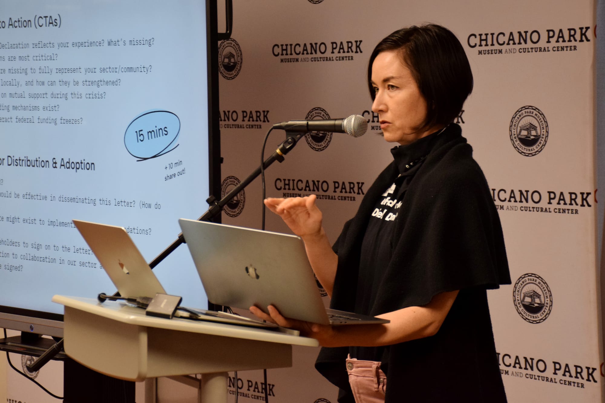A woman speaks at a podium holding a laptop
