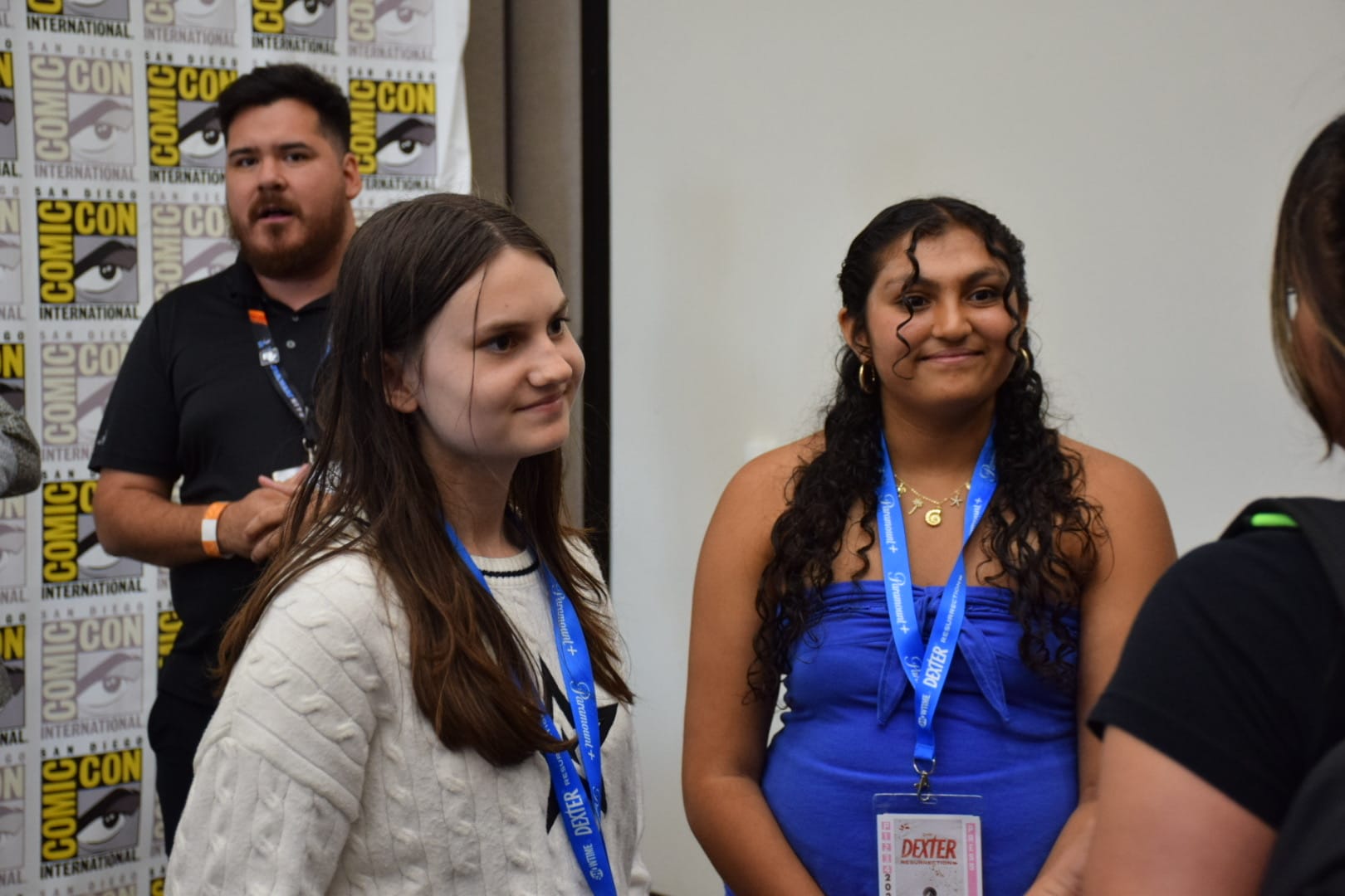 Two girls smile while talking to someone in a conference room