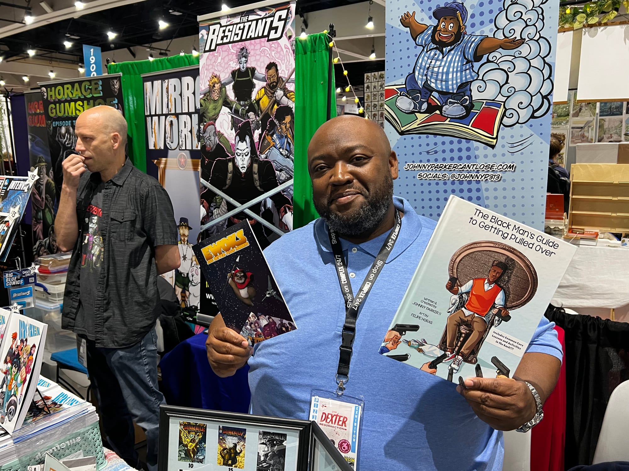 A man poses for a photo with two comic books in a convention center