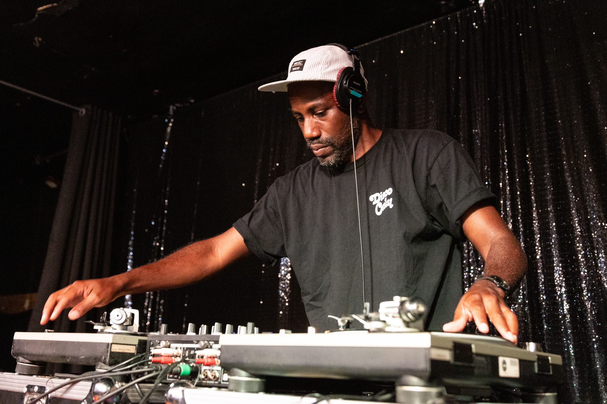 A person spins records at a DJ station on a stage