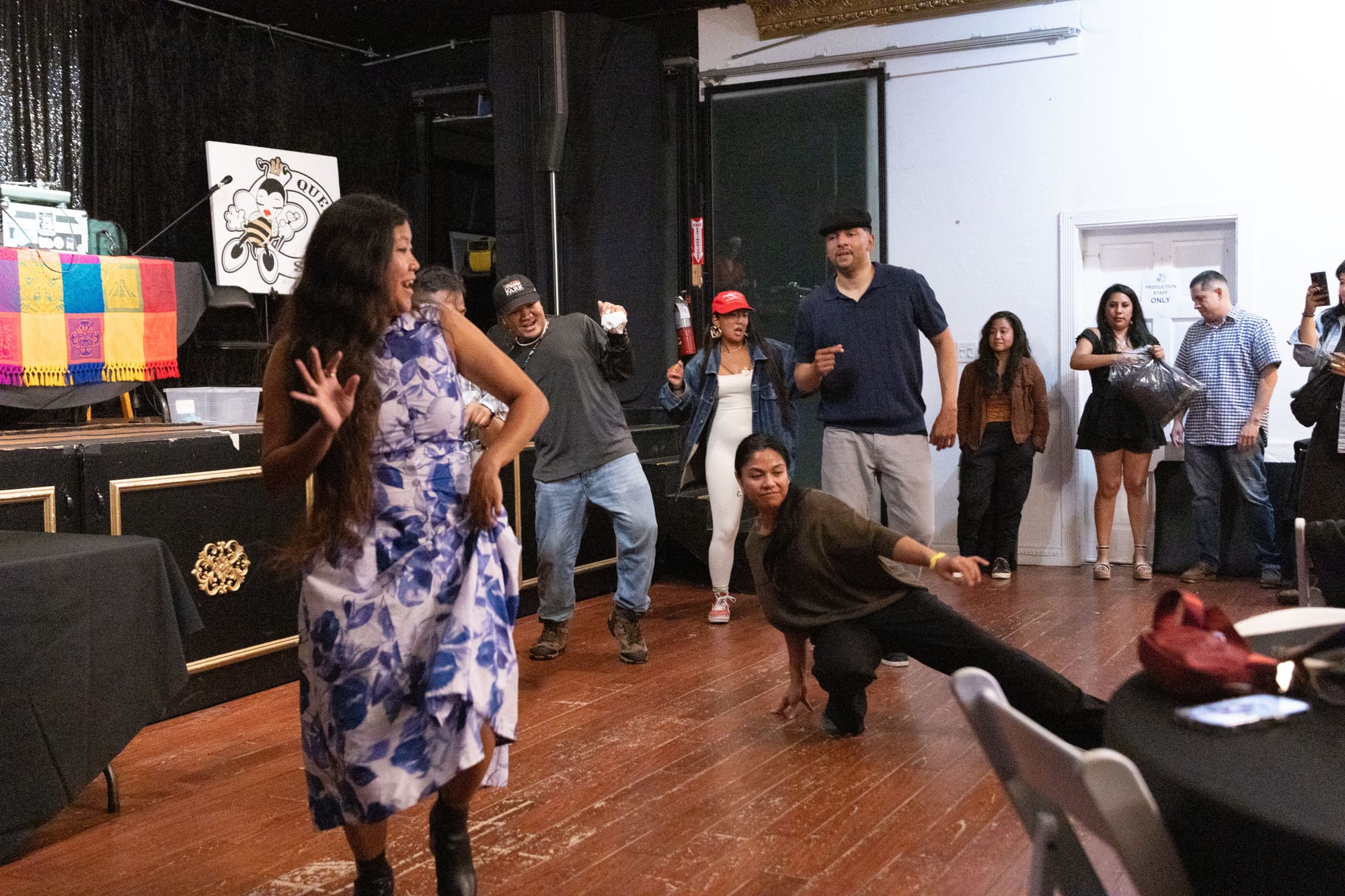 People dance in an event venue in front of a stage