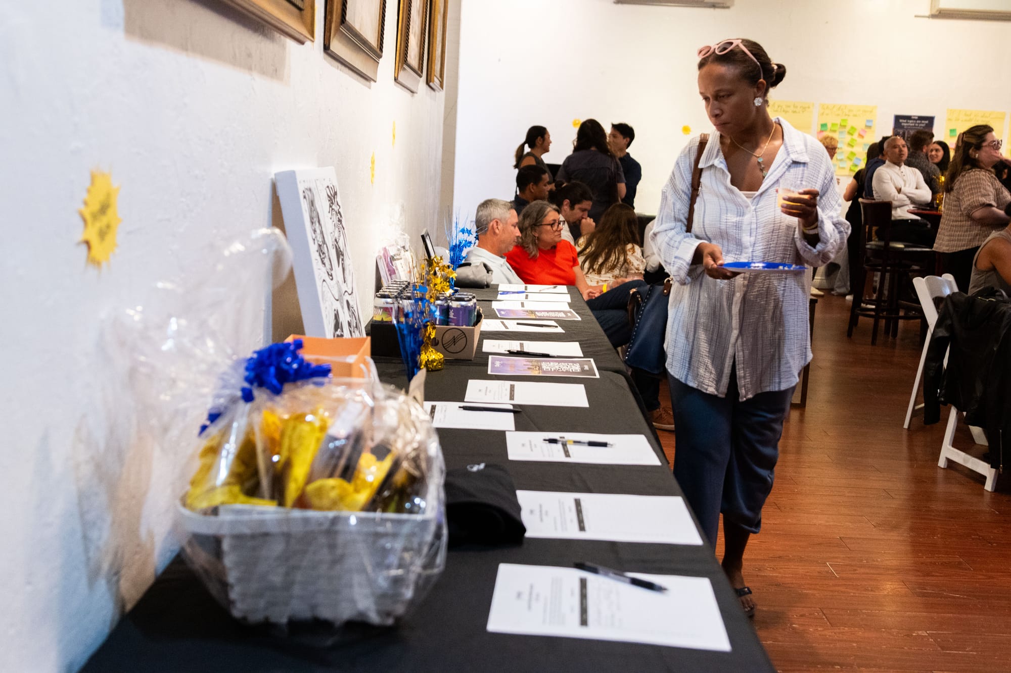 A person looks at a table of silent auction items at a party