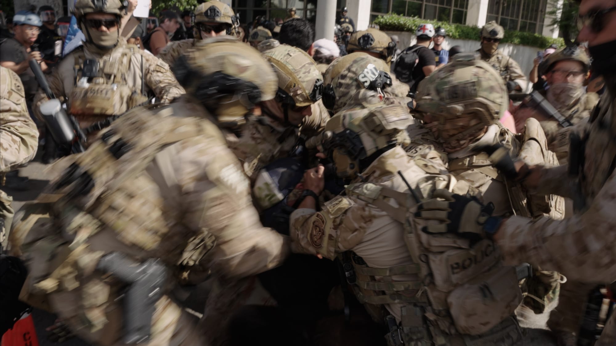 People in uniforms and helmets group together in the street