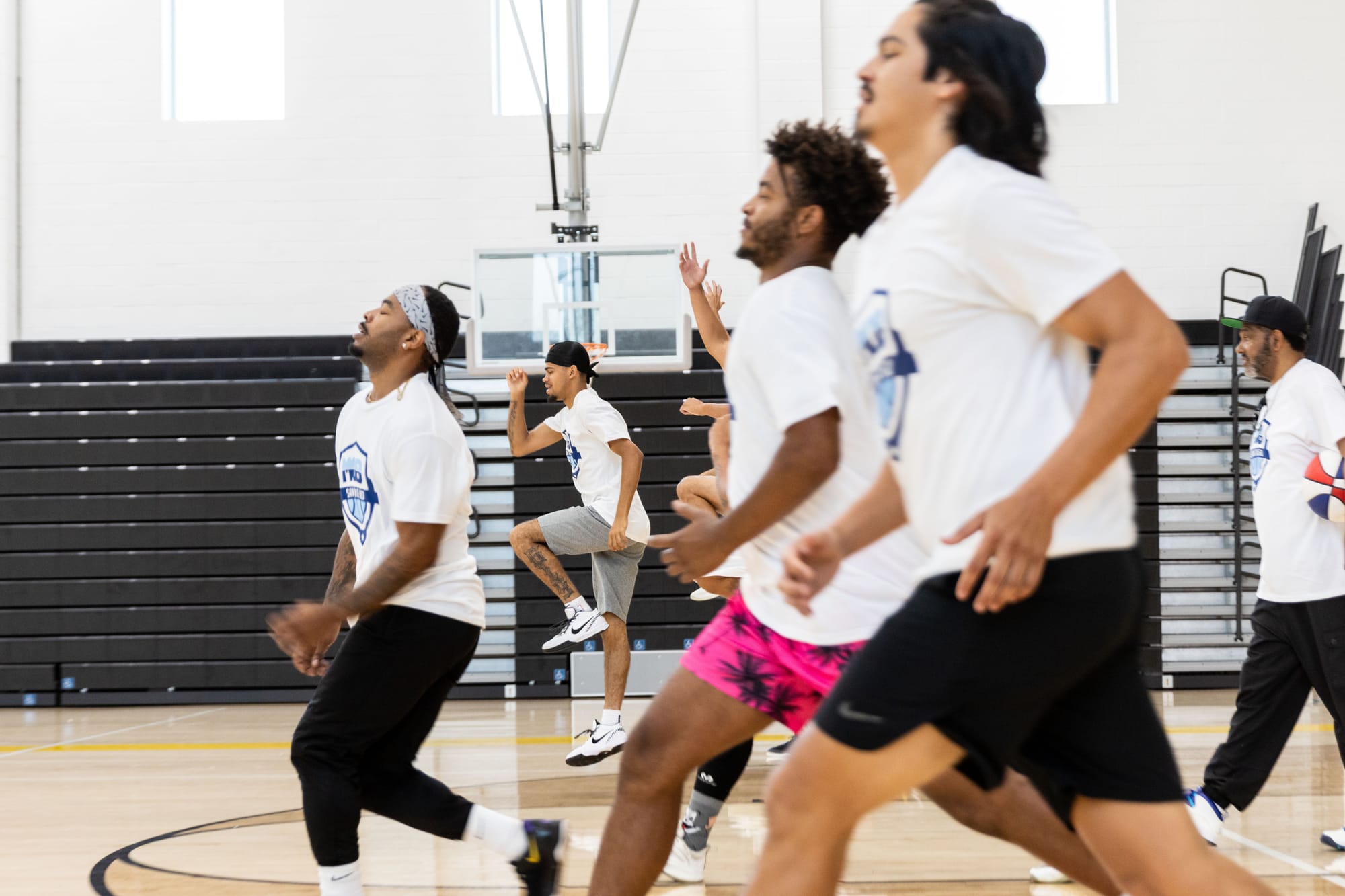 A group of people run across a gym in a basketball court