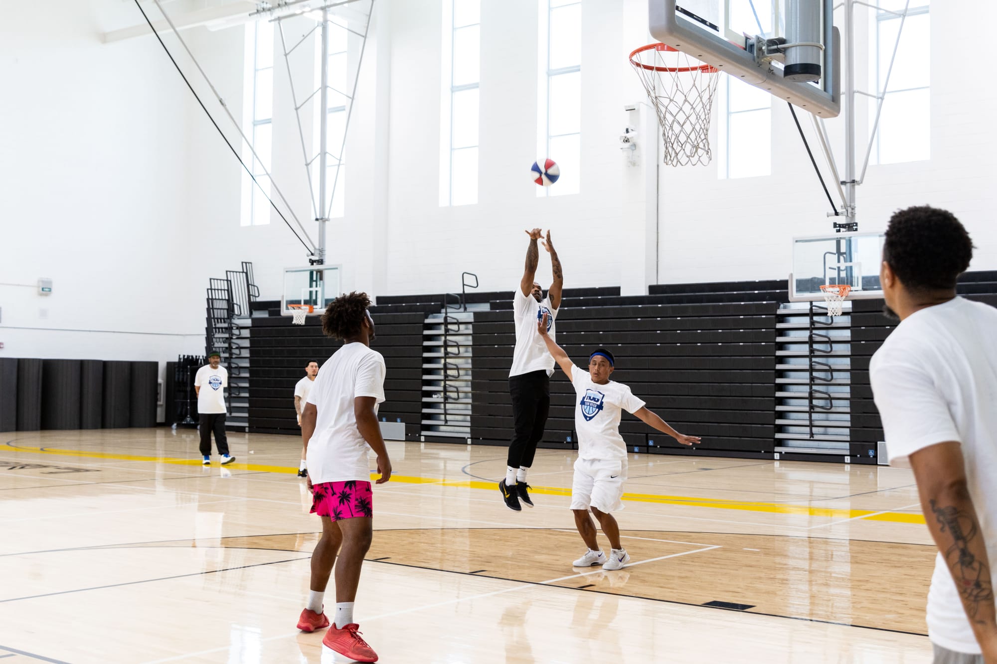 A group of people play basketball as one makes a shot