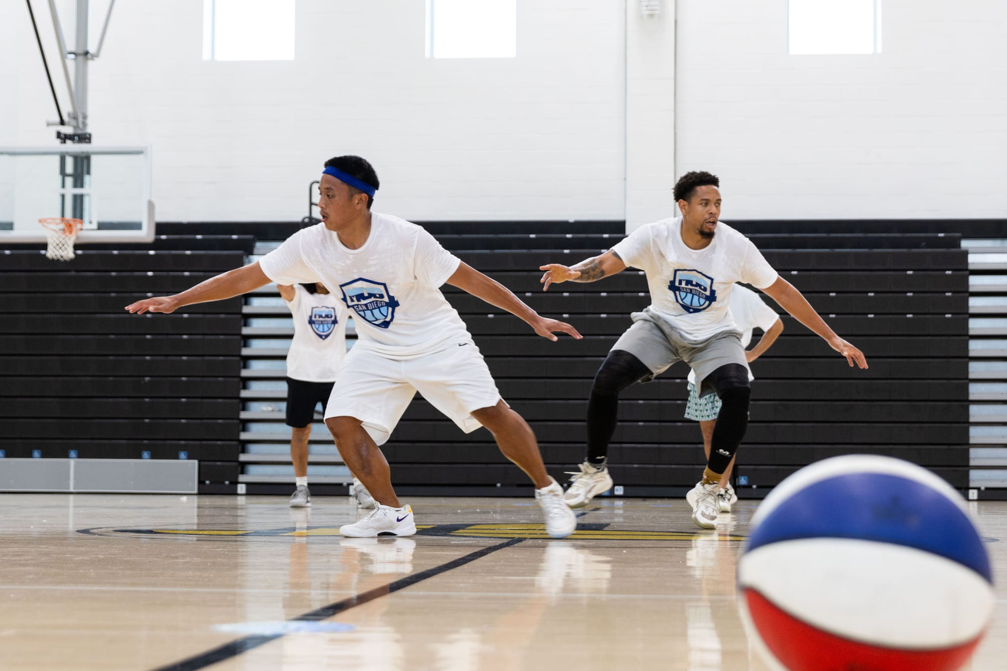 People do basketball drills in a court with a basketball on the ground in front of them