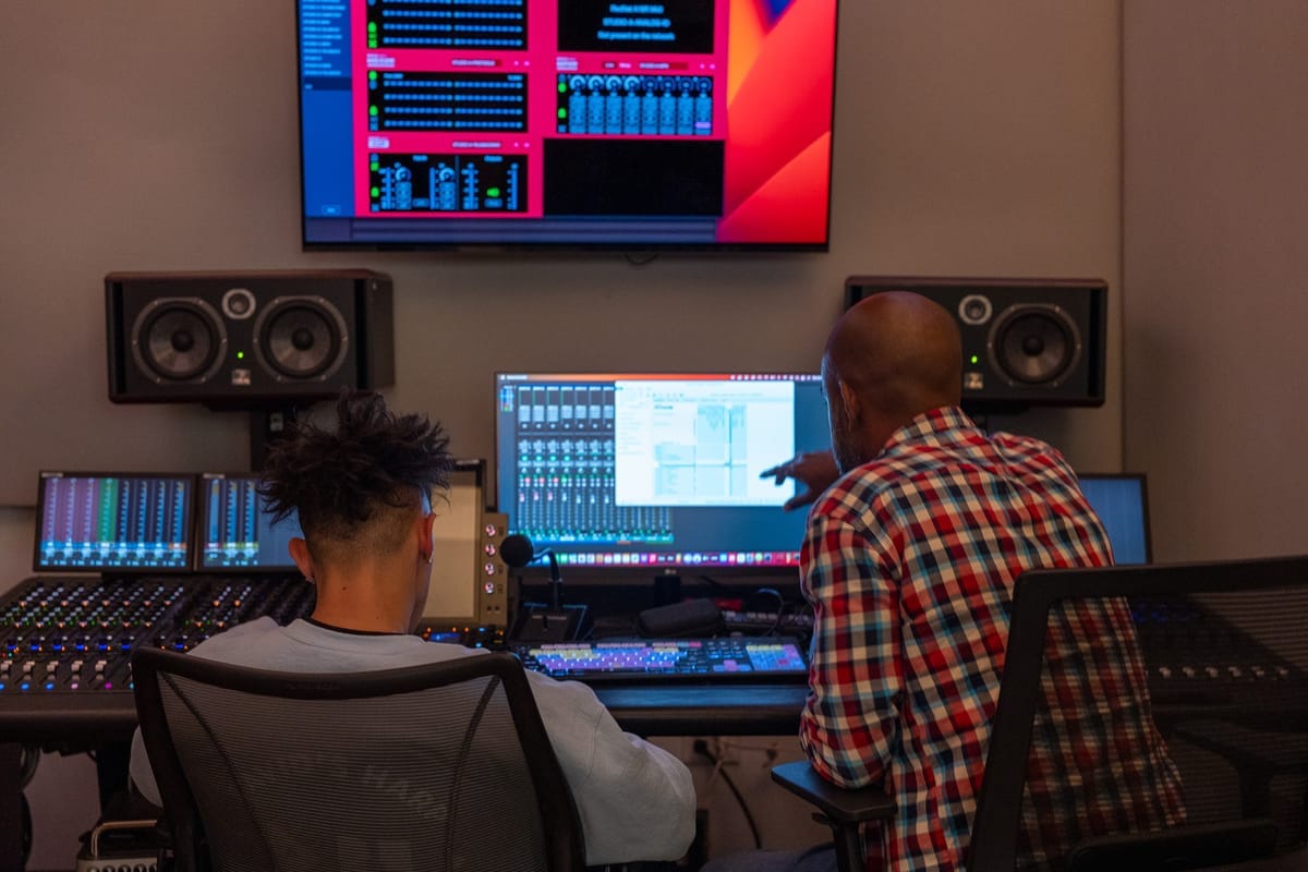 Two men work on computers mixing music 