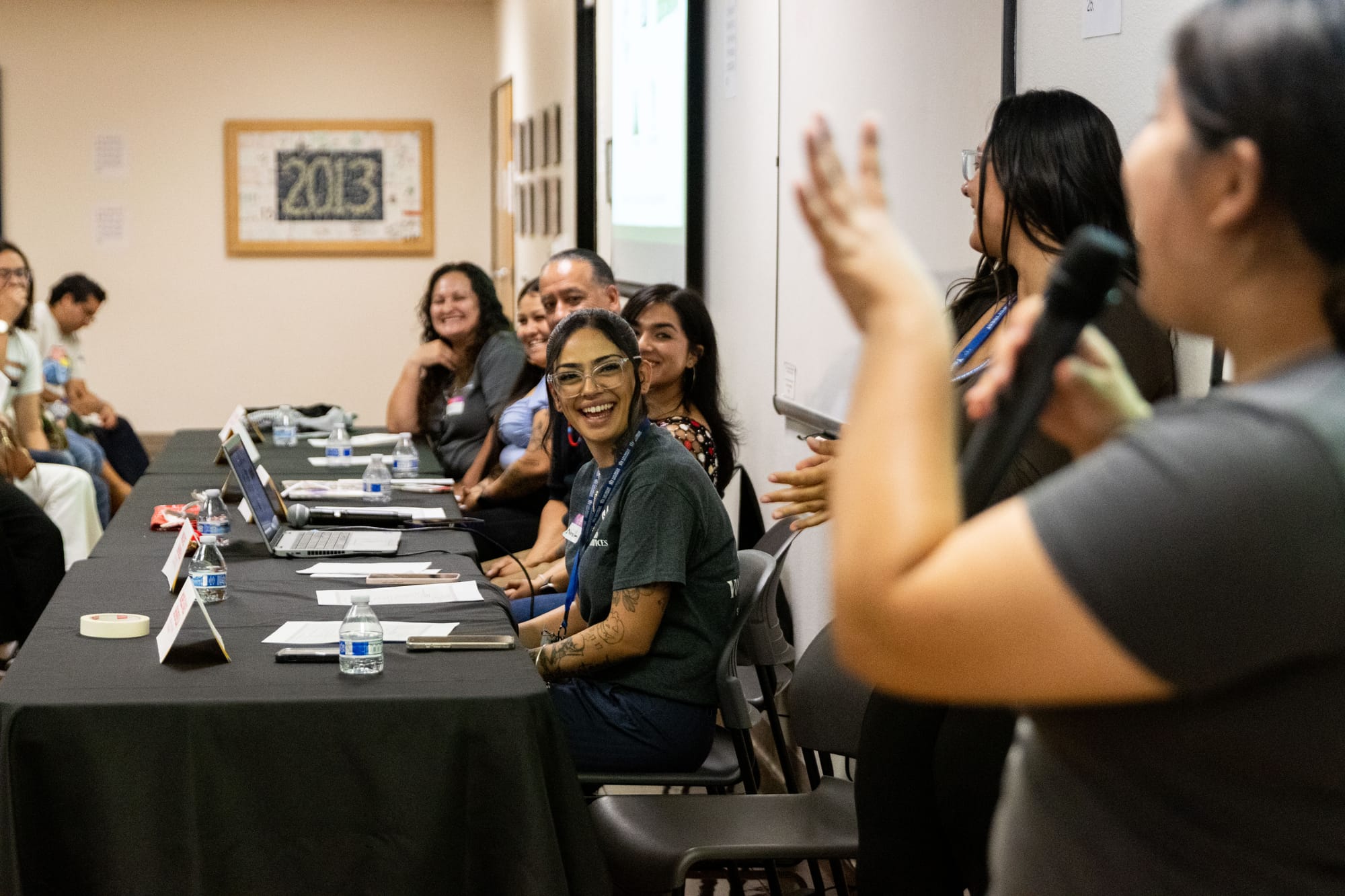 Panelists smile while listening to a young speaker