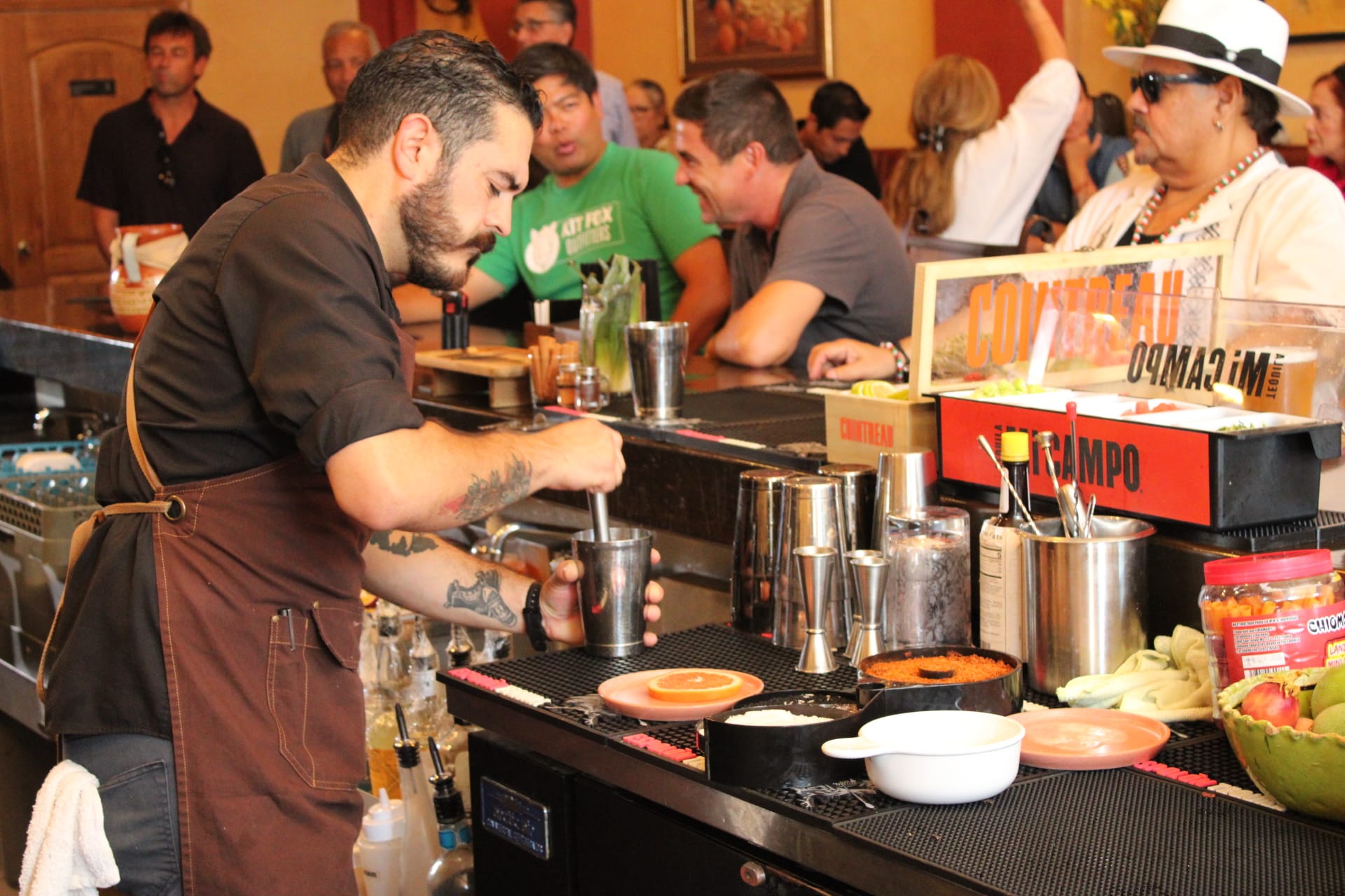 A bartender muddles a drink behind the bar at a restaurant 