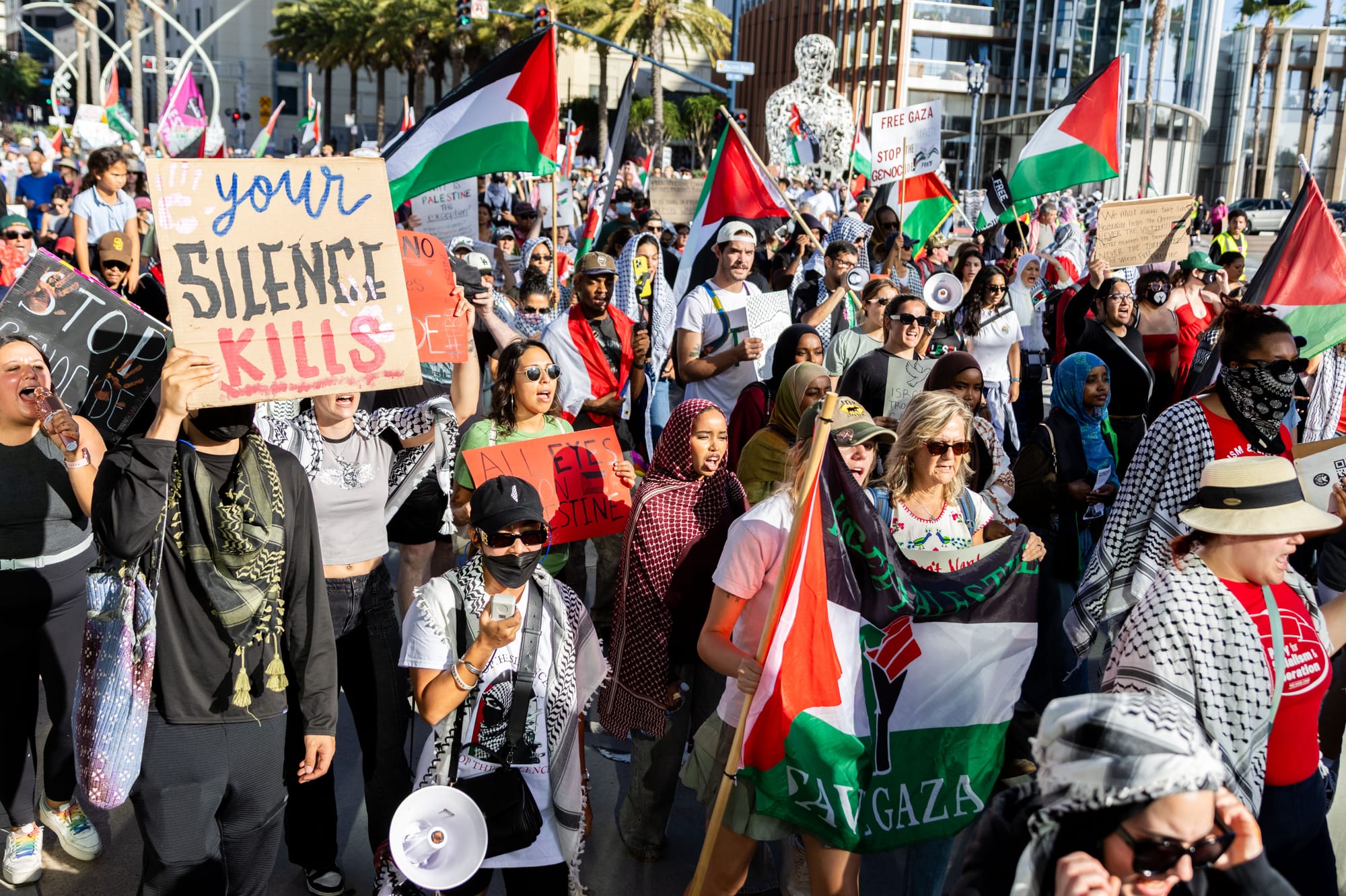 A large group of people march in a demonstration holding palestinian flags and signs