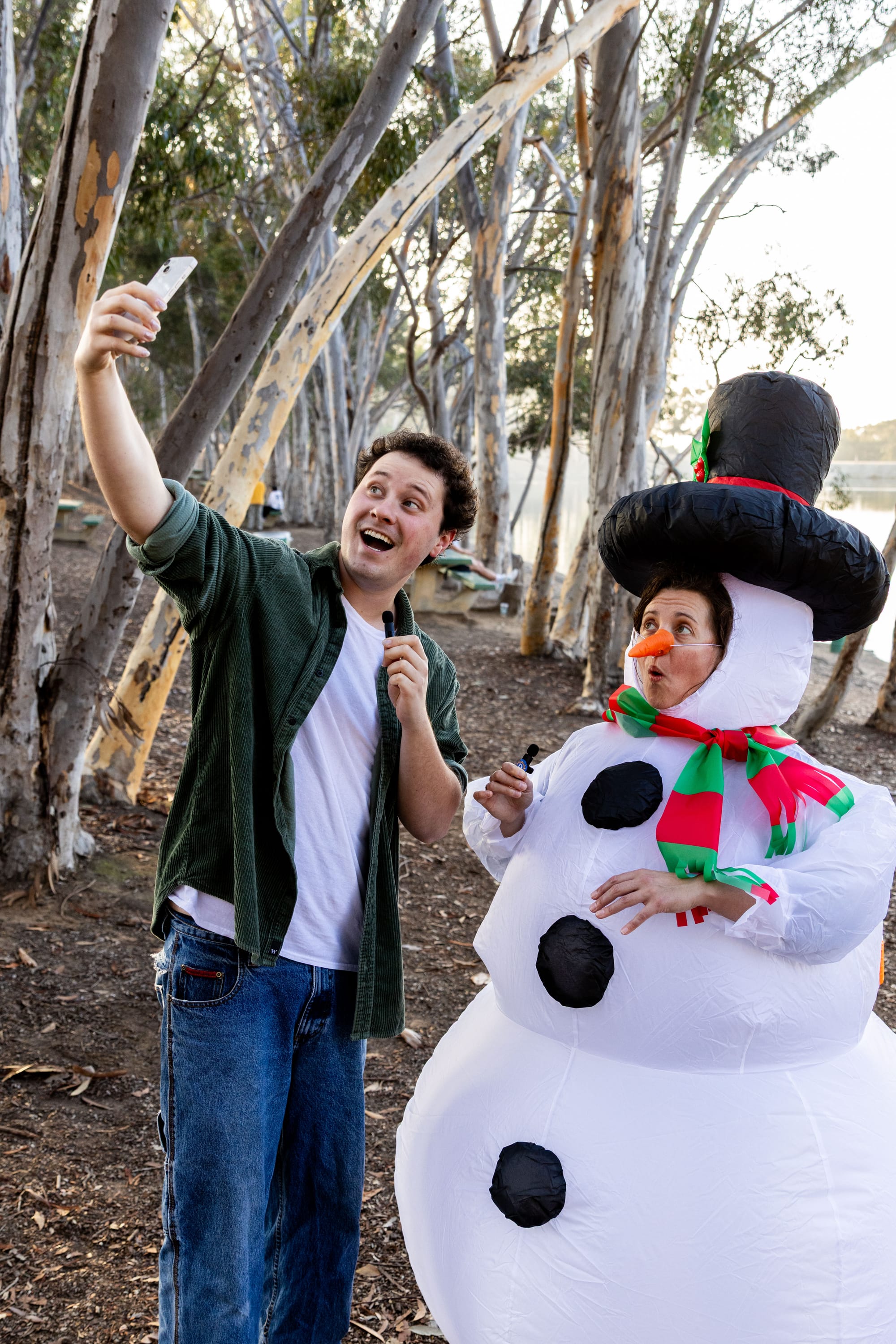 A person takes a selfie with someone dressed in a snowperson costume.
