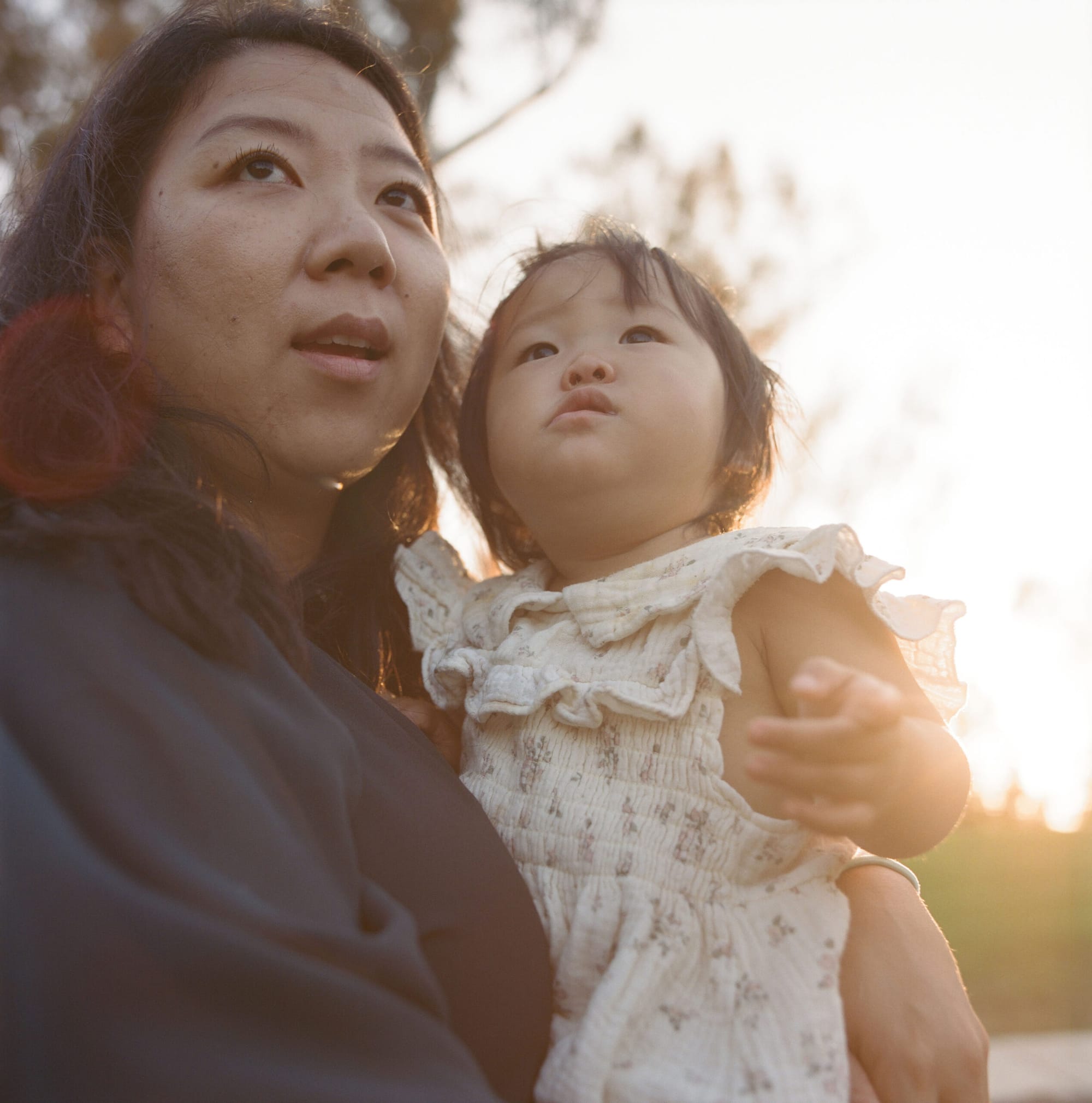 A woman holds her toddler outside