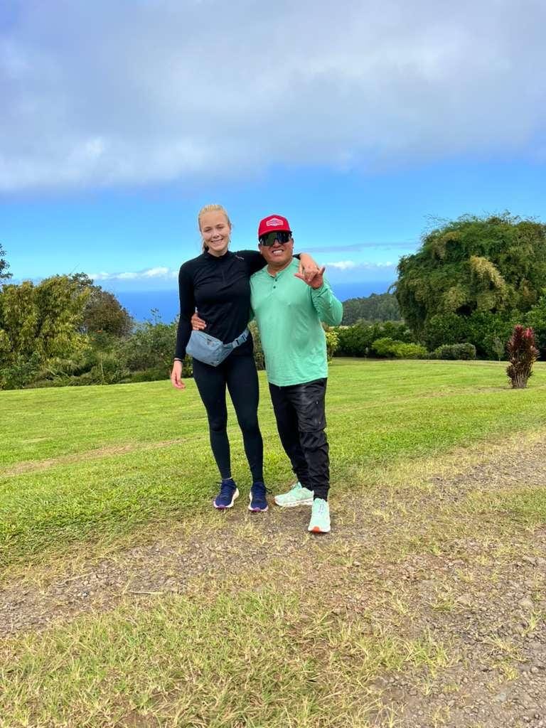 A woman in black athletic wear and a man in a green shirt and black pants stand in a field