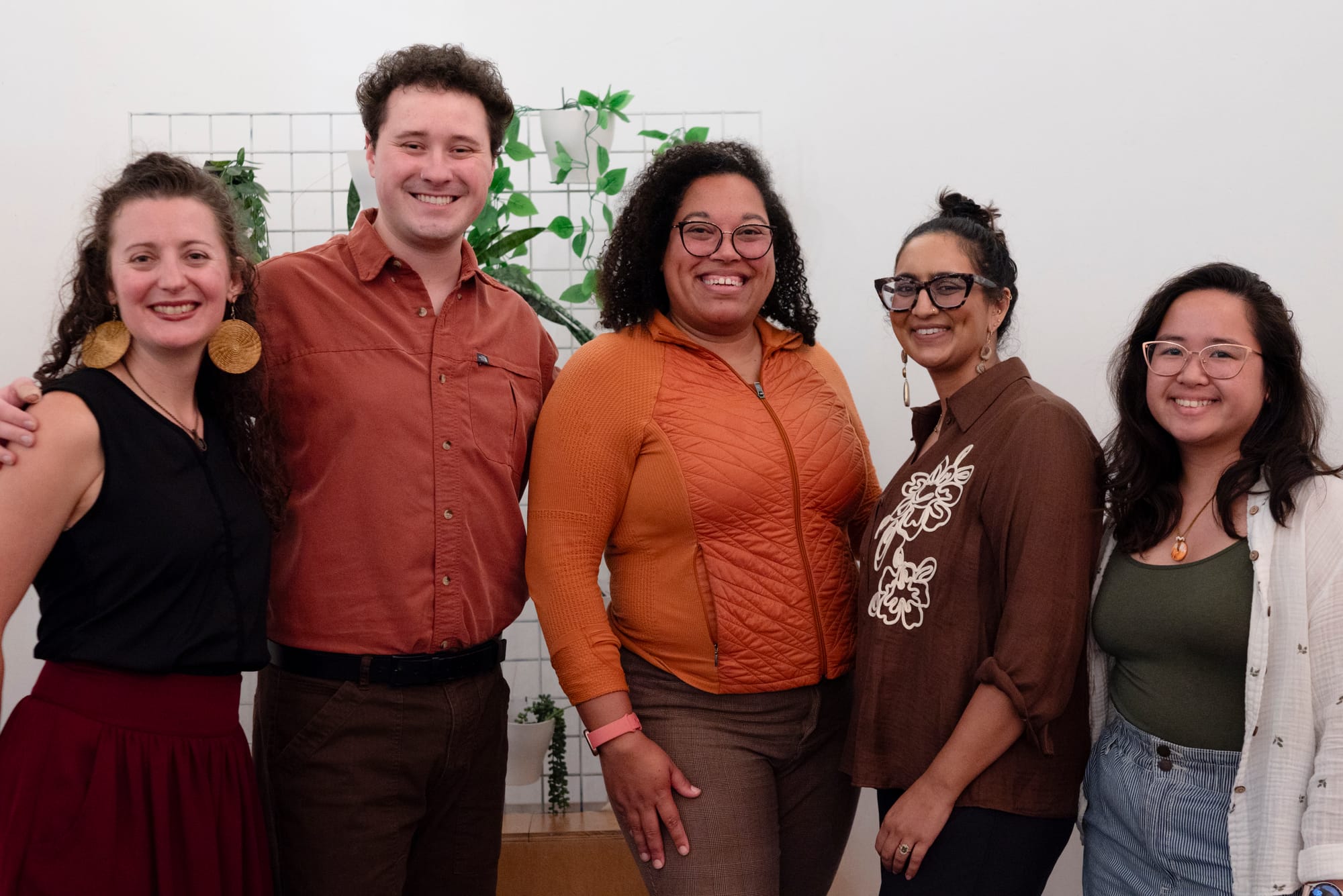 Five people pose for a photograph standing side by side