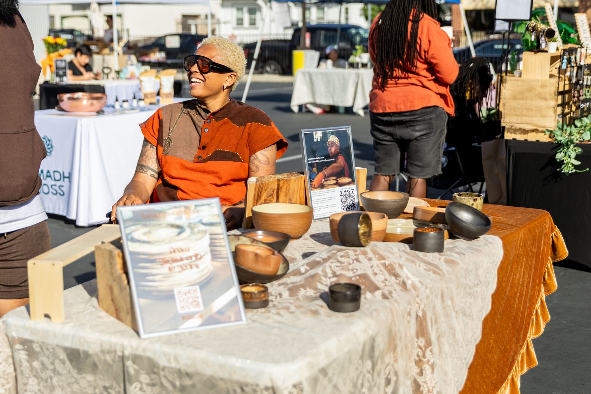 A woman speaks to someone at a outdoor market booth