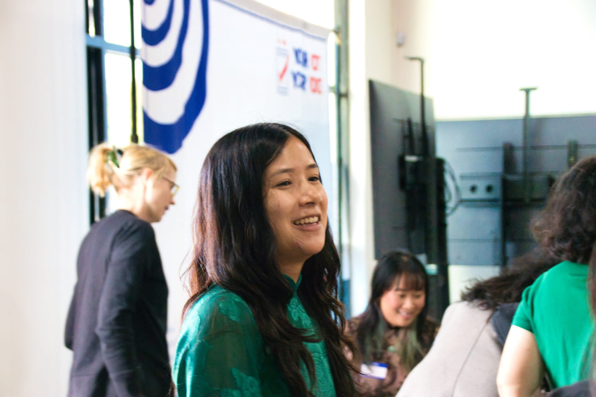 A woman with long, dark hair in a green dress smiles