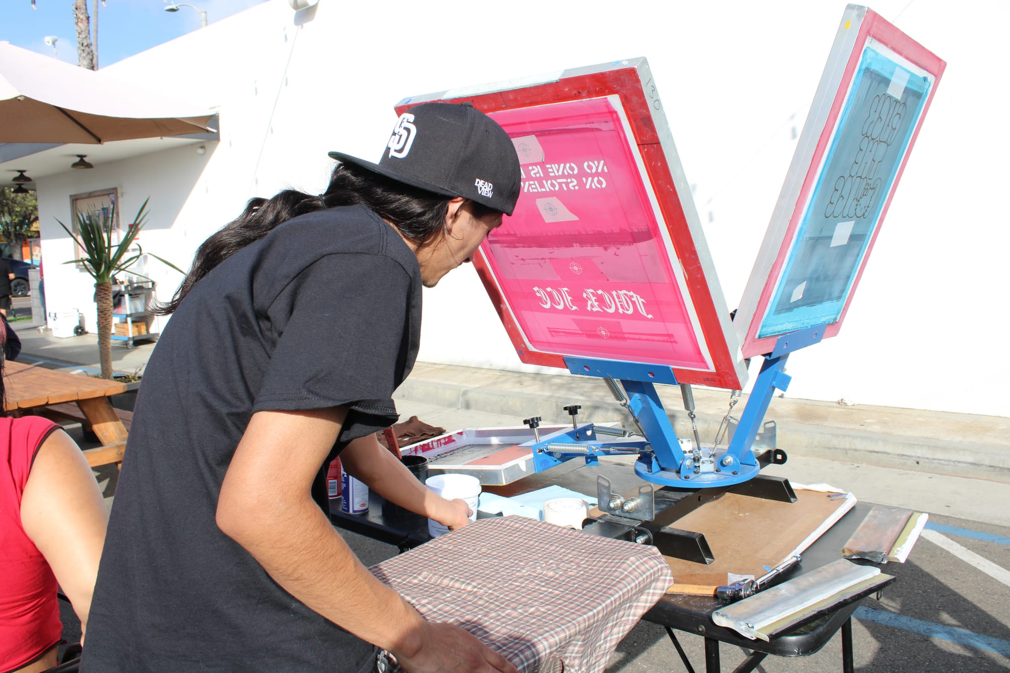 A man prepares to paint a shirt on a press.