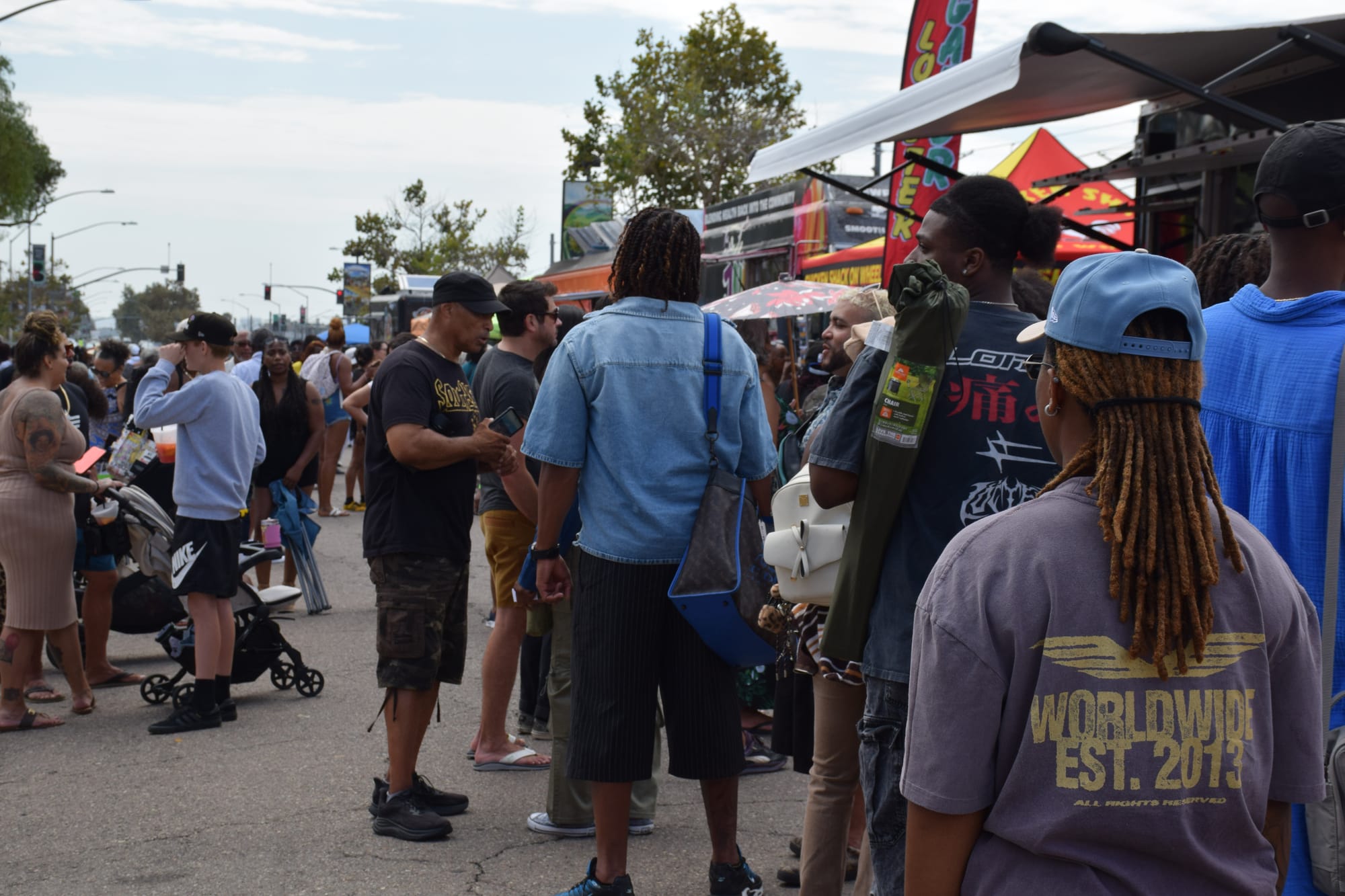 People walk around booths and food trucks at a street fair