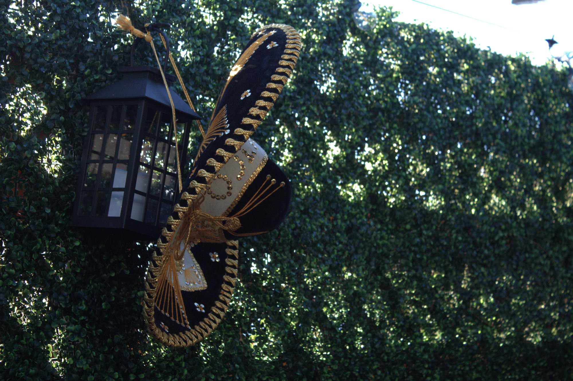 A black, white and gold sombrero hangs on a lantern.