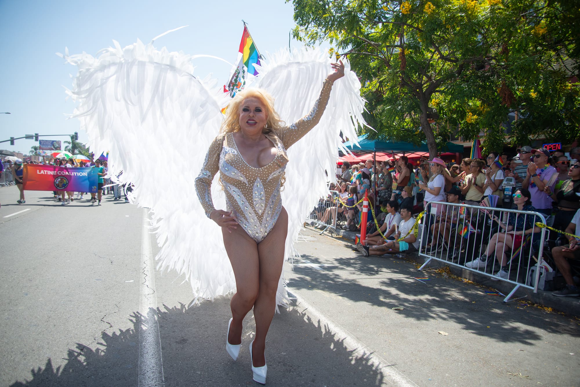 A person dressed as an angel with a shimmery leotard and large white wings and white heels