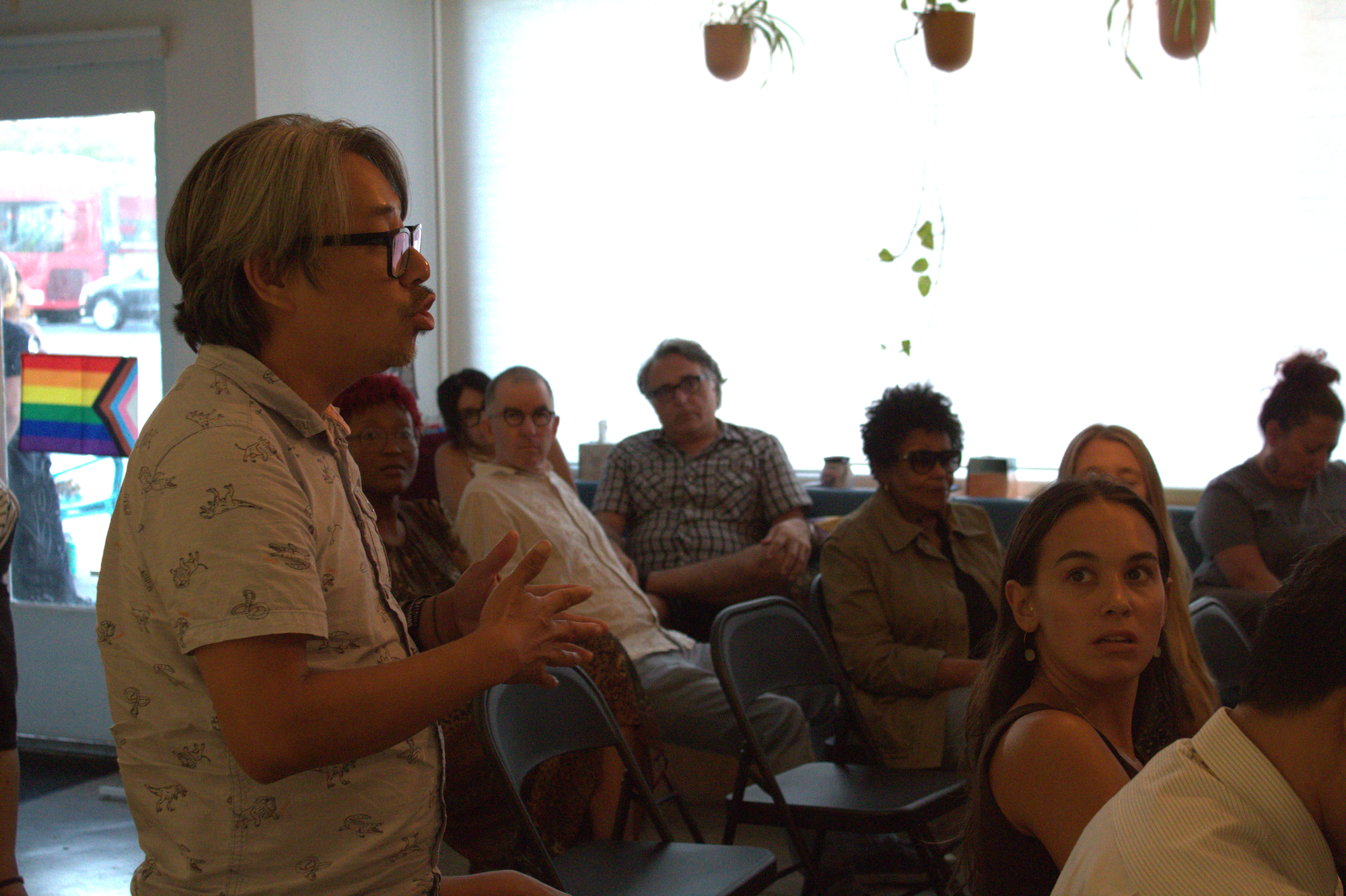 A man talks facing panelists while attendees to the left of him sitting down look in his direction 