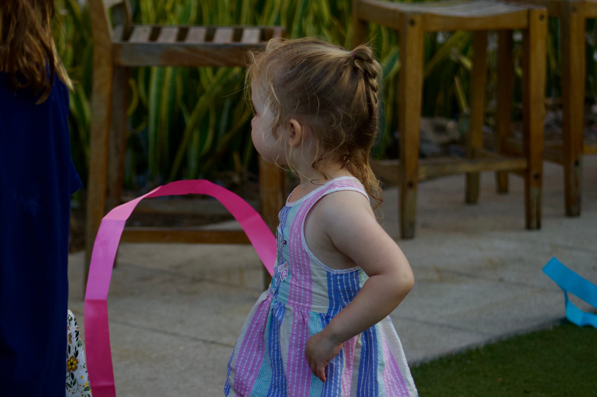 A kid plays with a pink ribbon outside