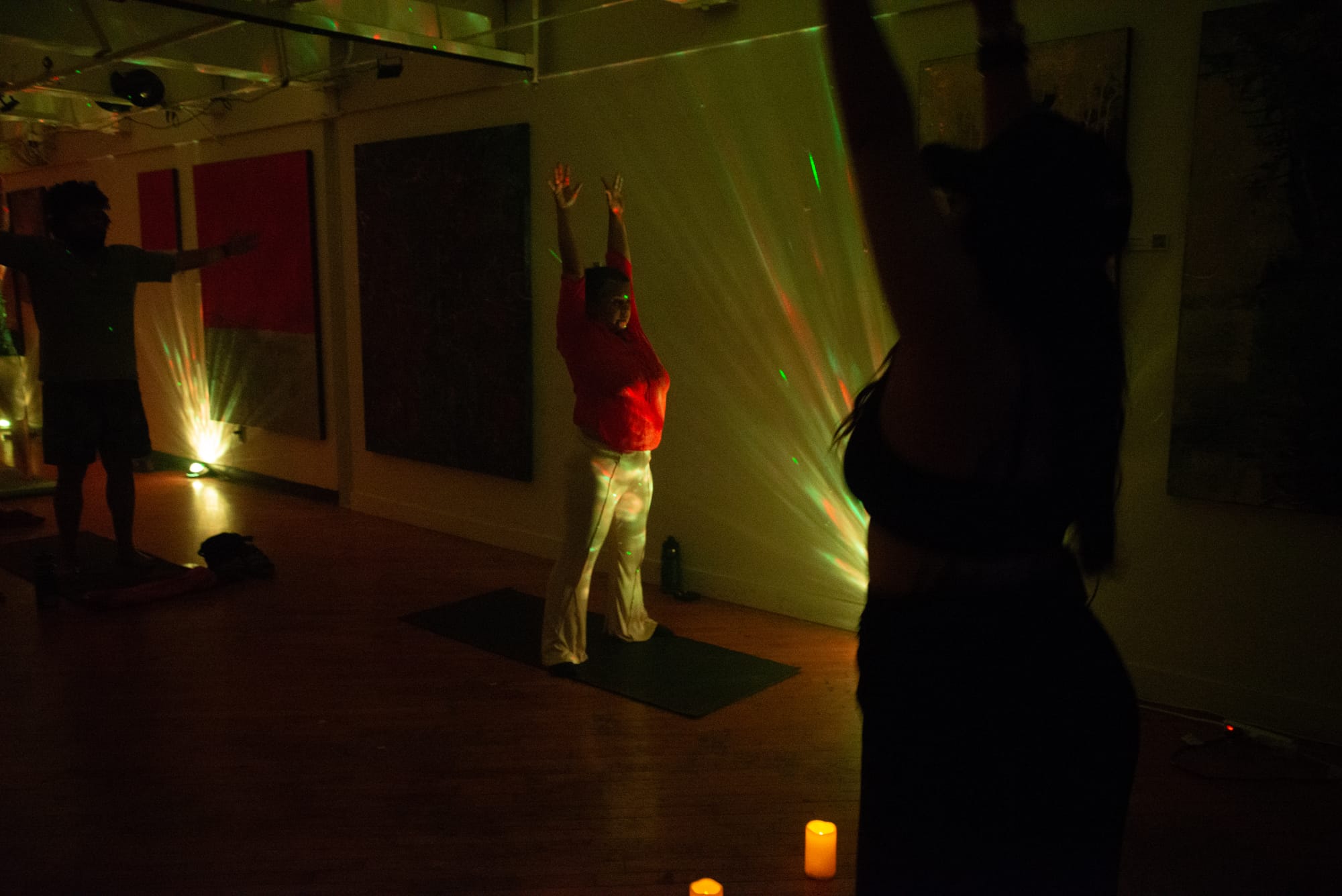 A woman in a reddish top reaches to the sky while standing on a yoga mat