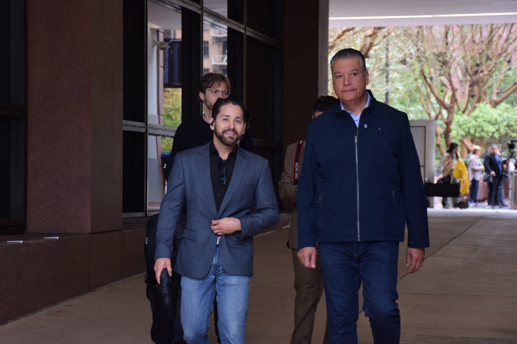 Four men walk through a covered walkway outside.