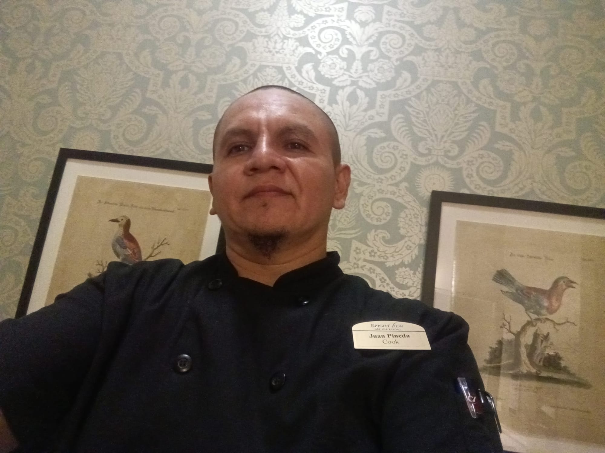 A man in cook's clothing with a nametag that says Juan Pineda Cook