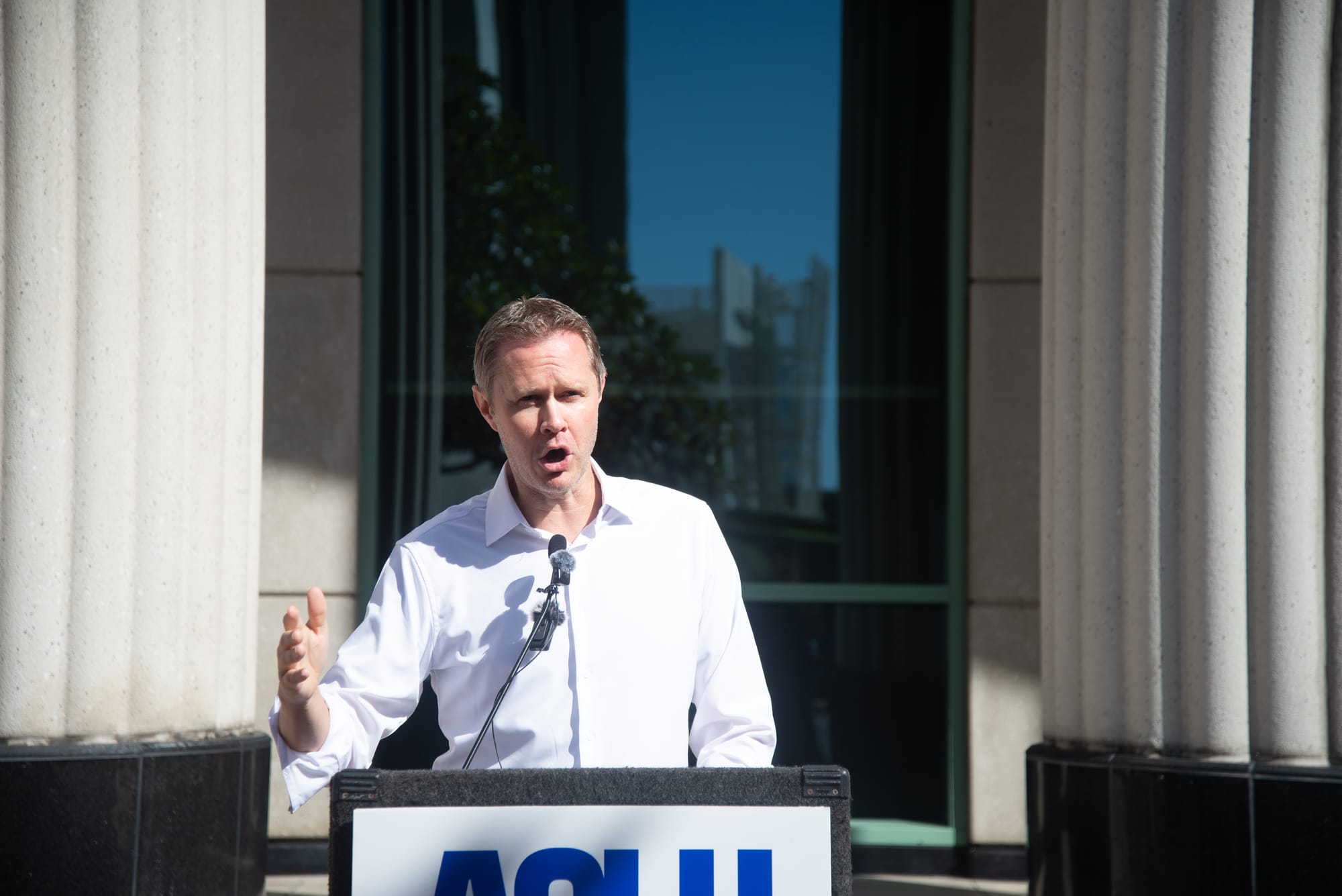 A man in a white shirt stands at a podium.