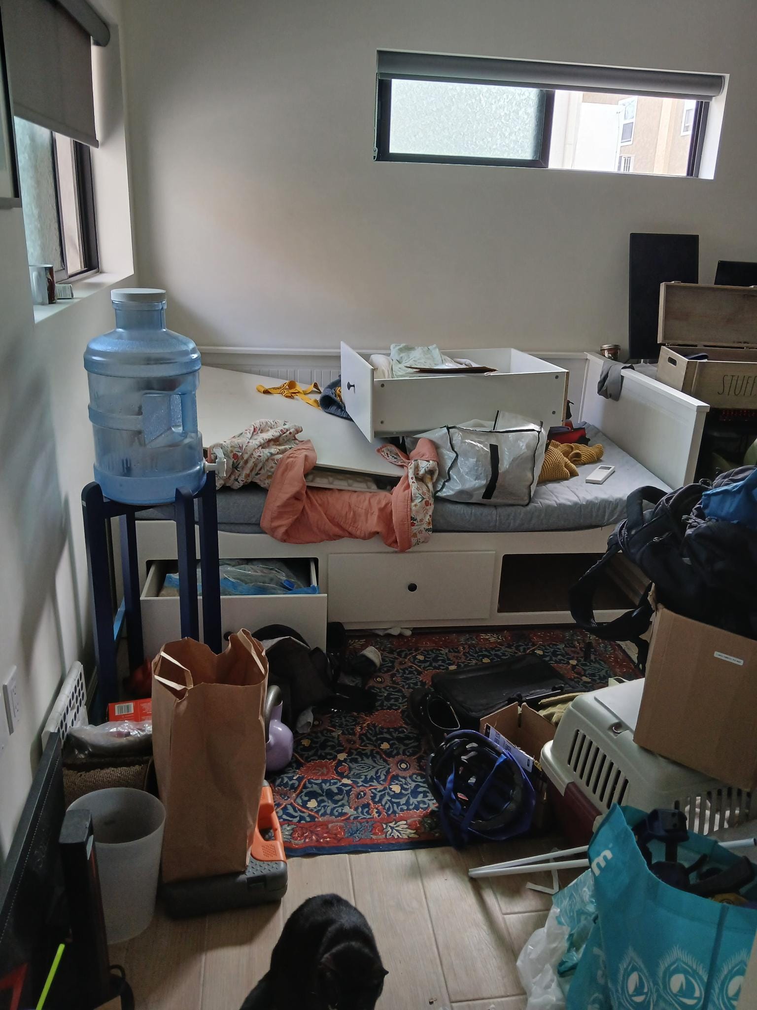 A daybed with shelves, clothing and other items lying on it in a haphazard way.