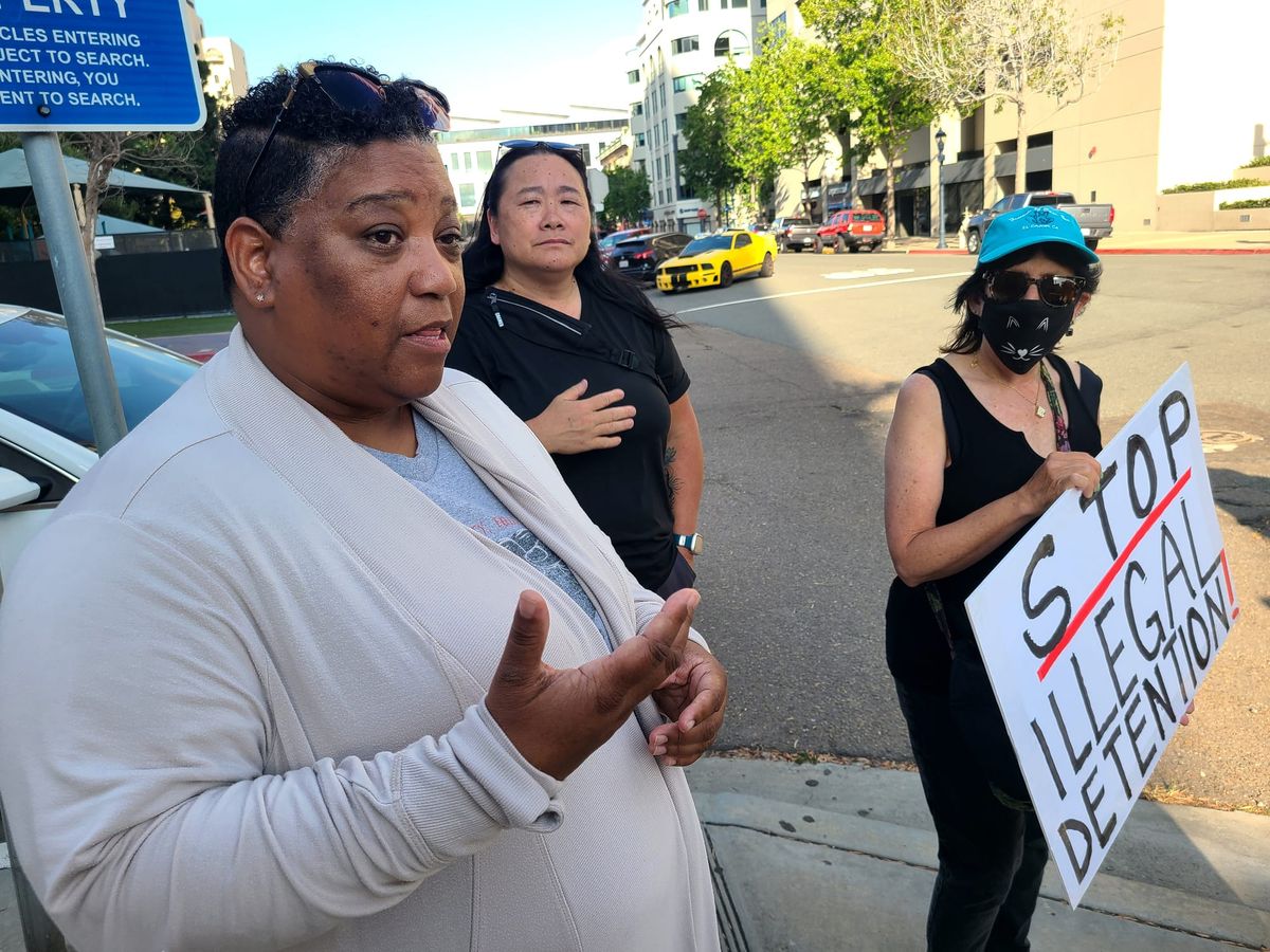 A woman talks on a street corner in front of two other people