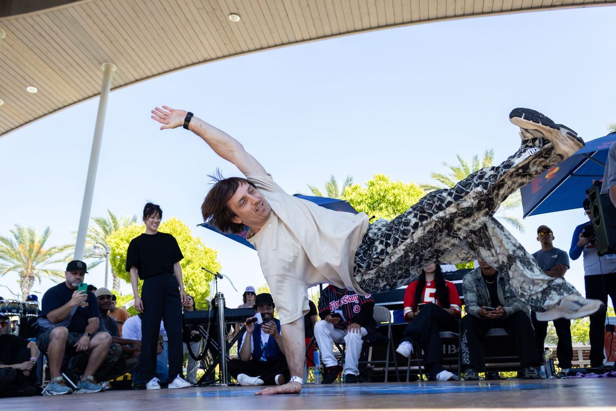 A dancer performs in a breaking competition outside in a park.
